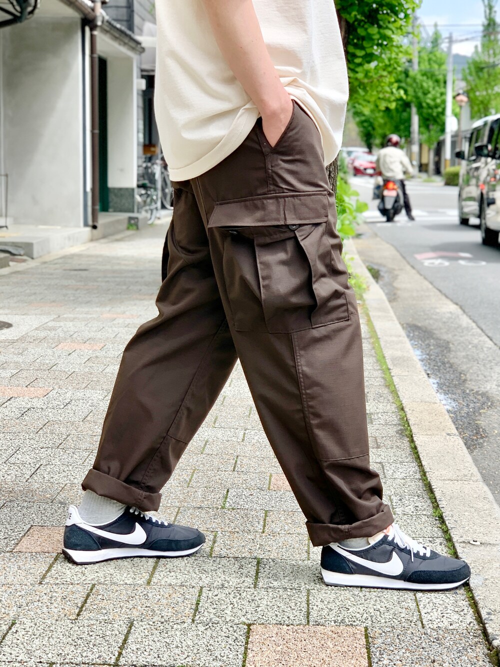 ブラウン系のカーゴパンツ、ベージュ系のTシャツ/カットソー、ブラック系のスニーカーを着用したメンズの夏コーディネートの5枚目の写真