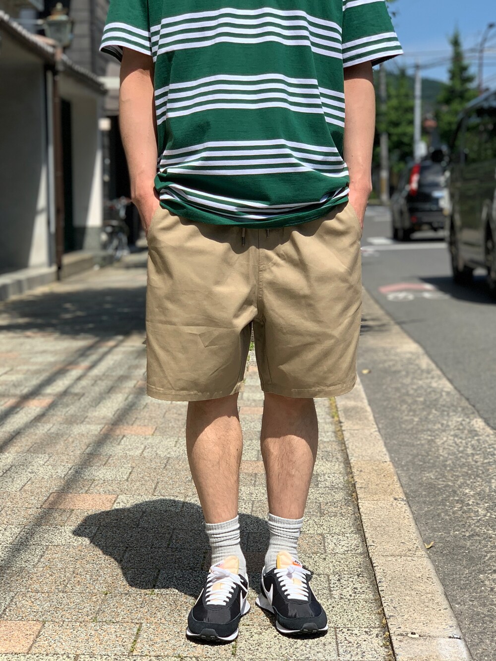 グリーン系のTシャツ/カットソー、ベージュ系のチノパンツ、ブラック系のスニーカーを着用したメンズの夏コーディネートの4枚目の写真