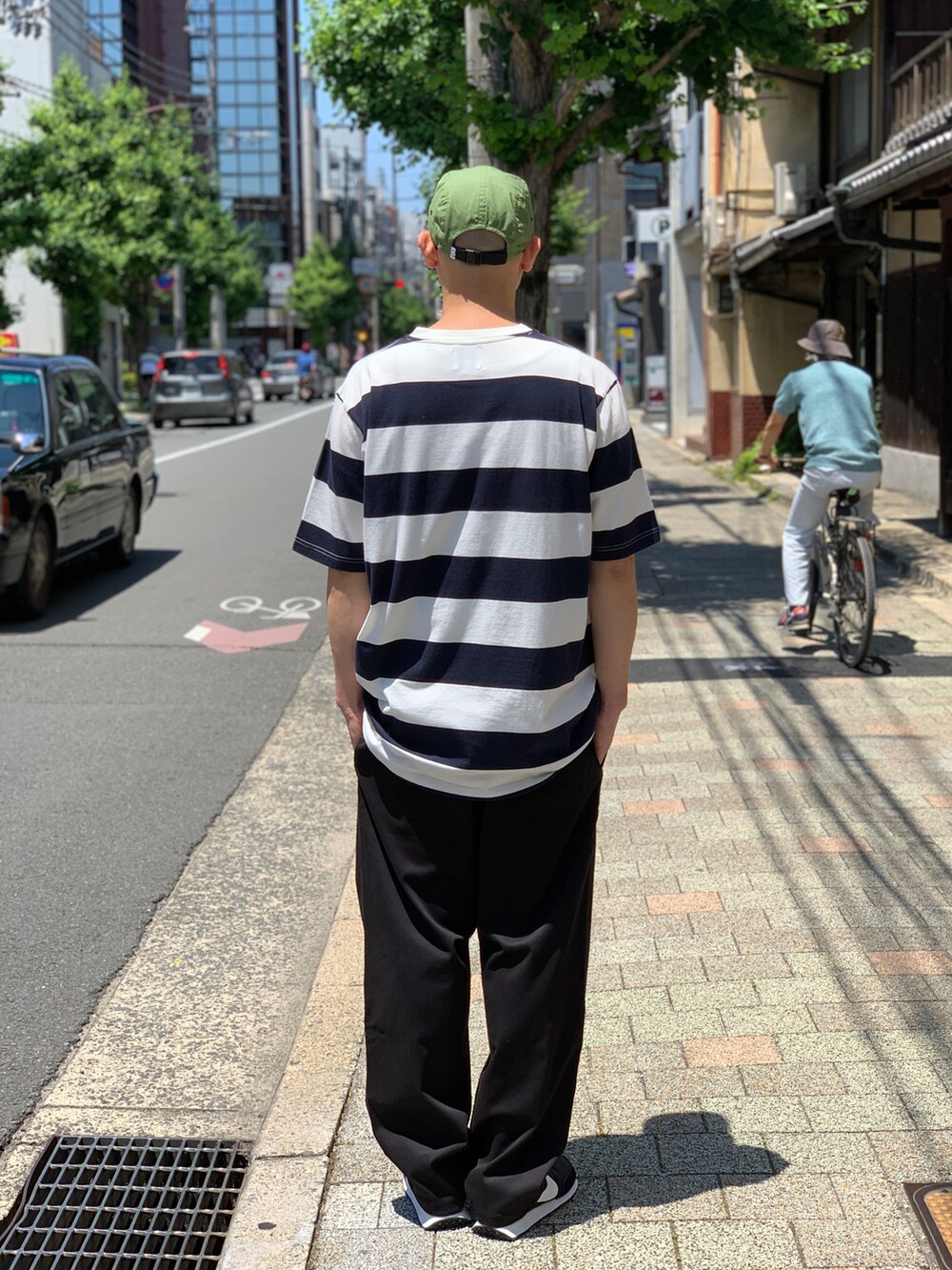 ブラック系のスニーカー、ブルー系のTシャツ/カットソー、ブラック系のチノパンツを着用したメンズの夏コーディネートの2枚目の写真