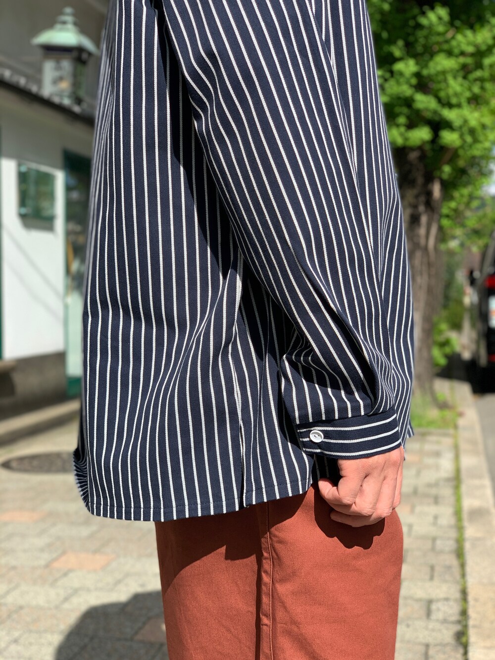 ブラック系のシャツ/ブラウス、ブラウン系のチノパンツ、ブラック系のスニーカーを着用したメンズの夏コーディネートの4枚目の写真