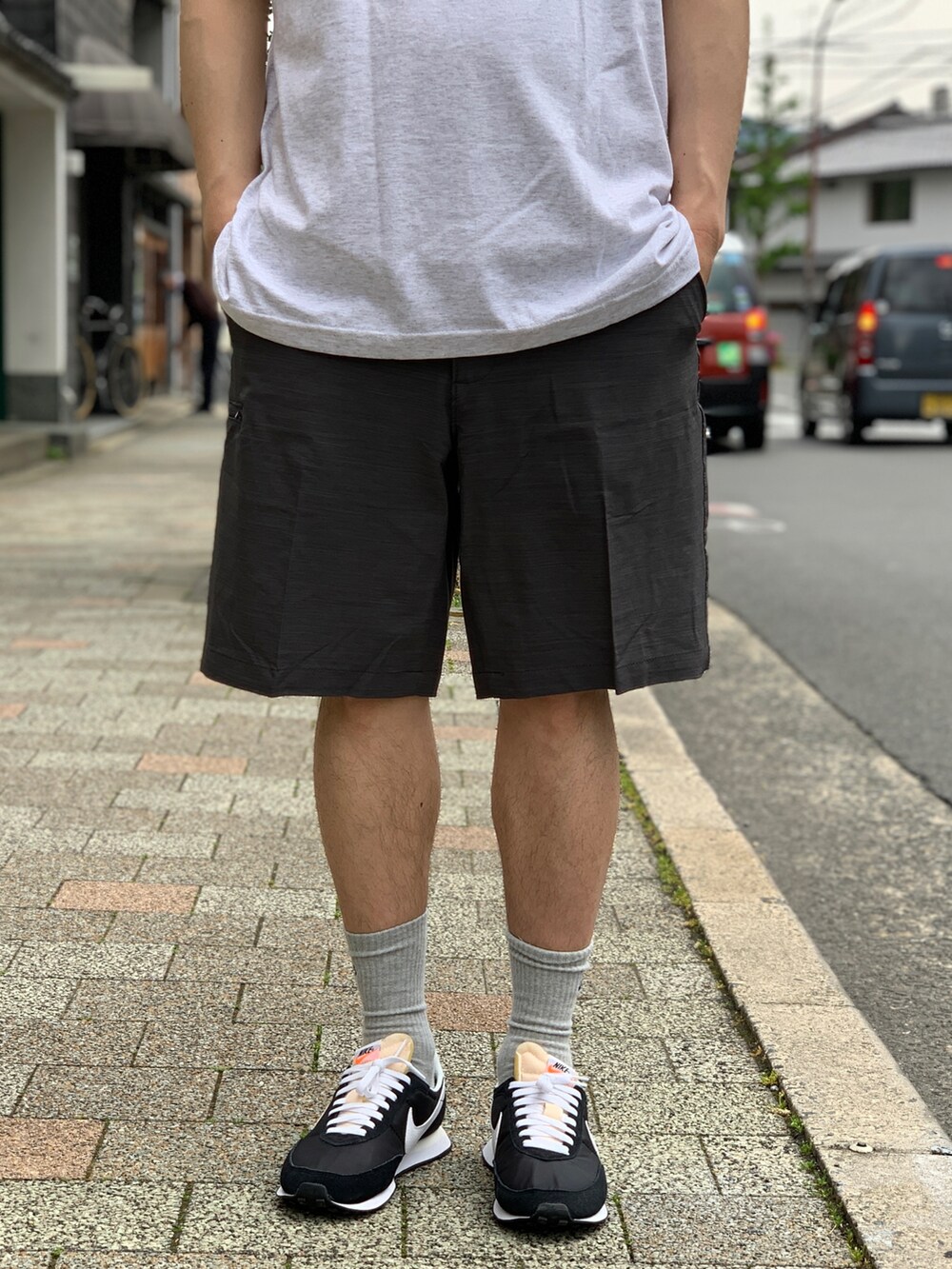 ブラック系のスニーカー、グレー系のチノパンツを着用したメンズの夏コーディネートの3枚目の写真