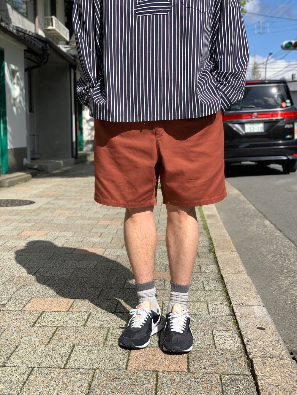 ブラック系のシャツ/ブラウス、ブラウン系のチノパンツ、ブラック系のスニーカーを着用したメンズの夏コーディネートの5枚目の写真