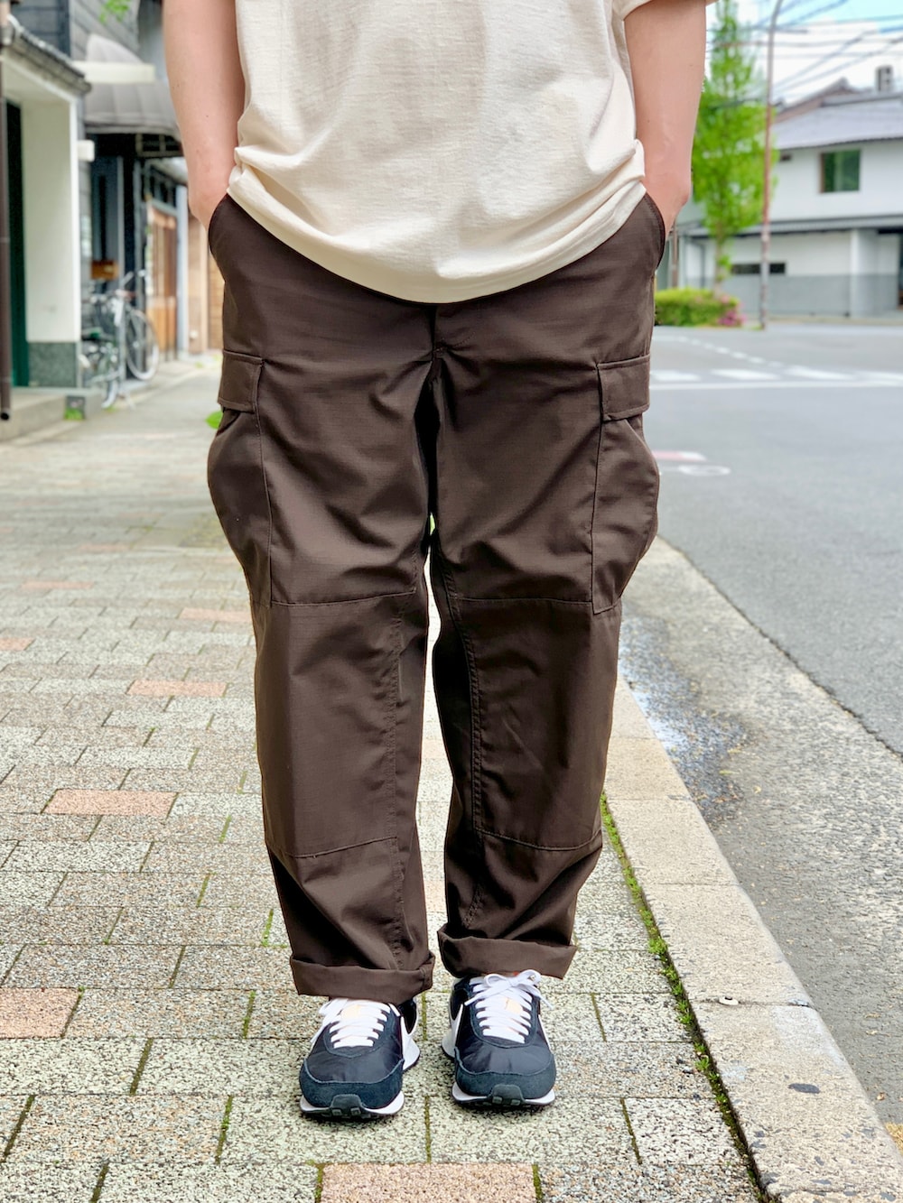 ブラウン系のカーゴパンツ、ベージュ系のTシャツ/カットソー、ブラック系のスニーカーを着用したメンズの夏コーディネートの4枚目の写真