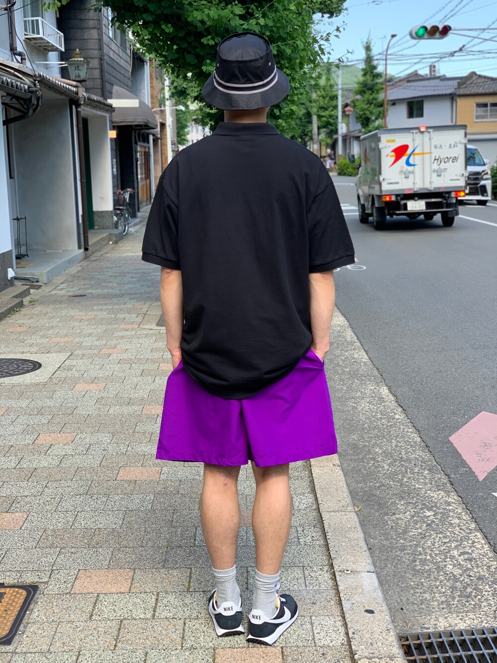 ブラック系のポロシャツ、パープル系のその他パンツ、ブラック系のスニーカーを着用したメンズの夏コーディネートの2枚目の写真