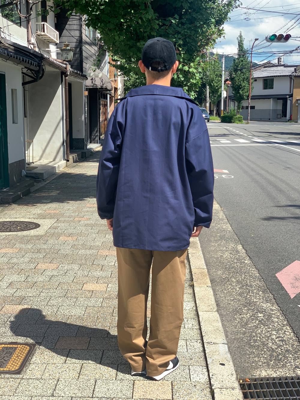 ベージュ系のチノパンツ、ブルー系のジャケット/アウター、ブラック系のスニーカーを着用したメンズの秋コーディネートの2枚目の写真