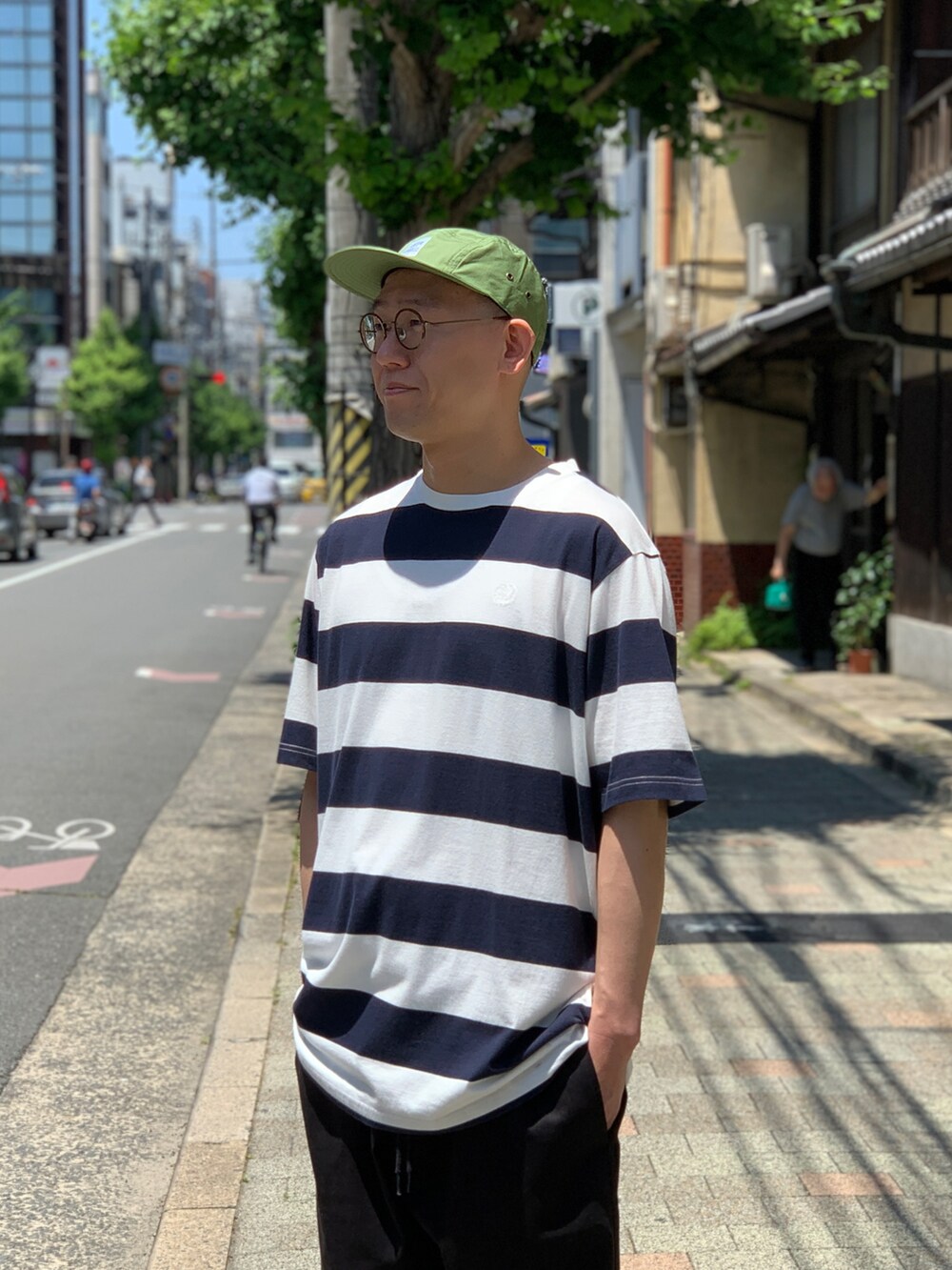 ブラック系のスニーカー、ブルー系のTシャツ/カットソー、ブラック系のチノパンツを着用したメンズの夏コーディネートの3枚目の写真