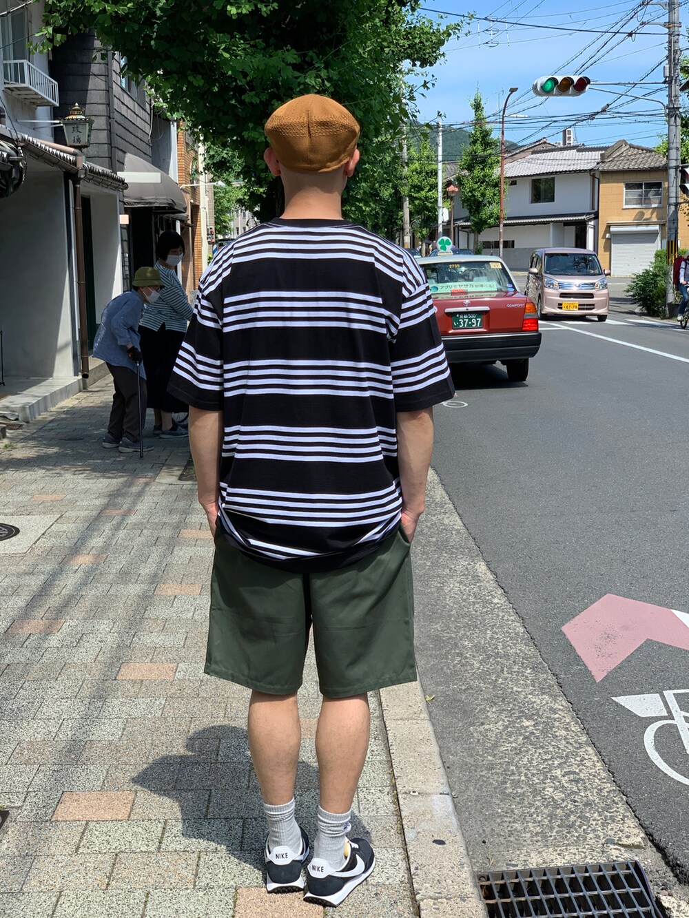 ブラック系のTシャツ/カットソー、グリーン系のチノパンツ、ブラック系のスニーカーを着用したメンズの夏コーディネートの2枚目の写真