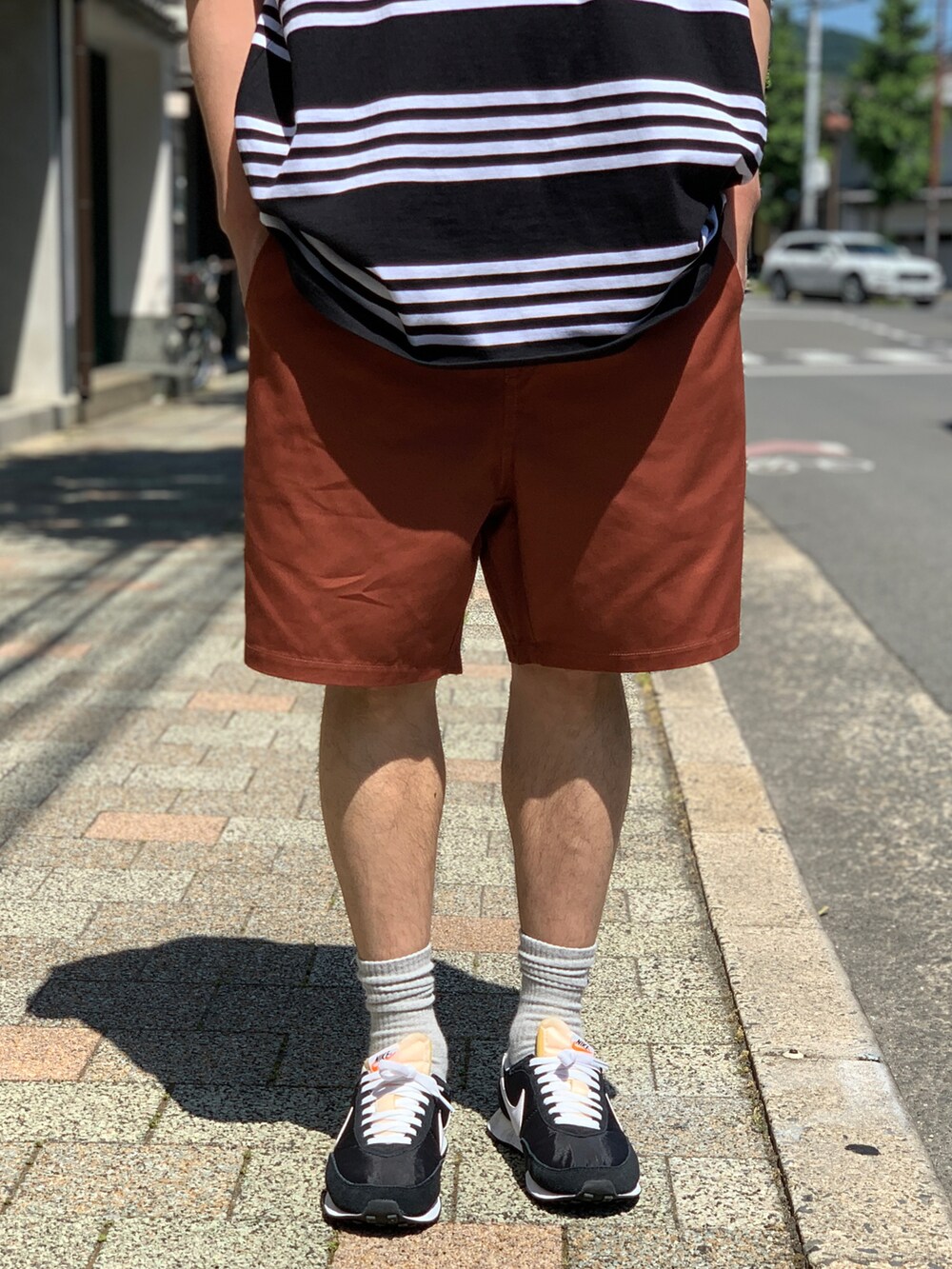 ブラック系のTシャツ/カットソー、ブラウン系のチノパンツ、ブラック系のスニーカーを着用したメンズの夏コーディネートの4枚目の写真