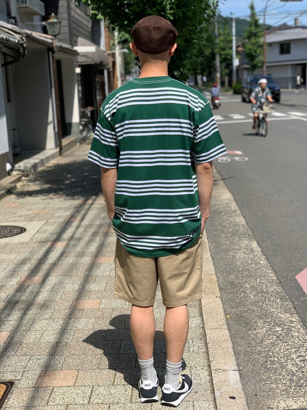 グリーン系のTシャツ/カットソー、ベージュ系のチノパンツ、ブラック系のスニーカーを着用したメンズの夏コーディネートの2枚目の写真
