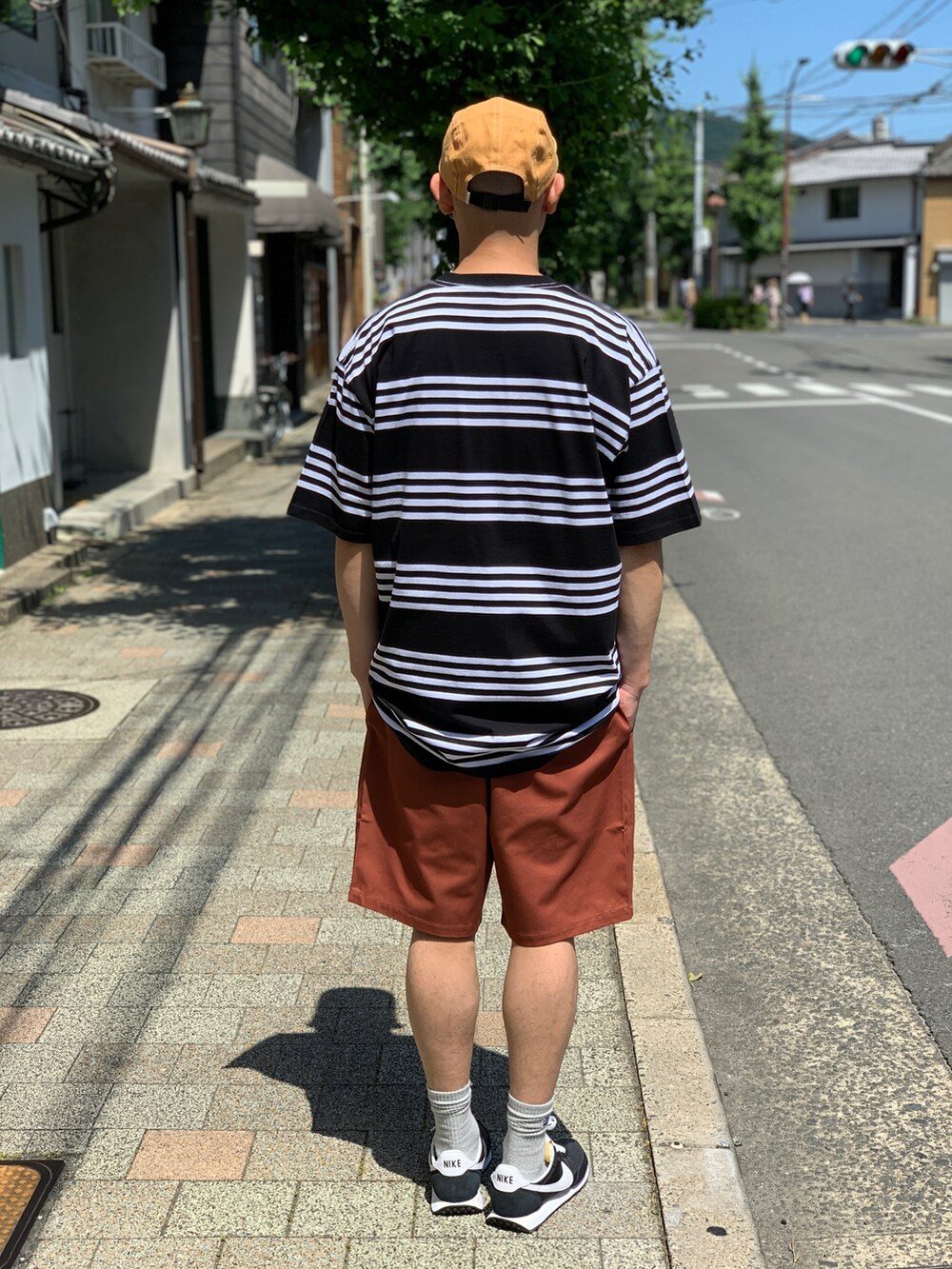 ブラック系のTシャツ/カットソー、ブラウン系のチノパンツ、ブラック系のスニーカーを着用したメンズの夏コーディネートの2枚目の写真