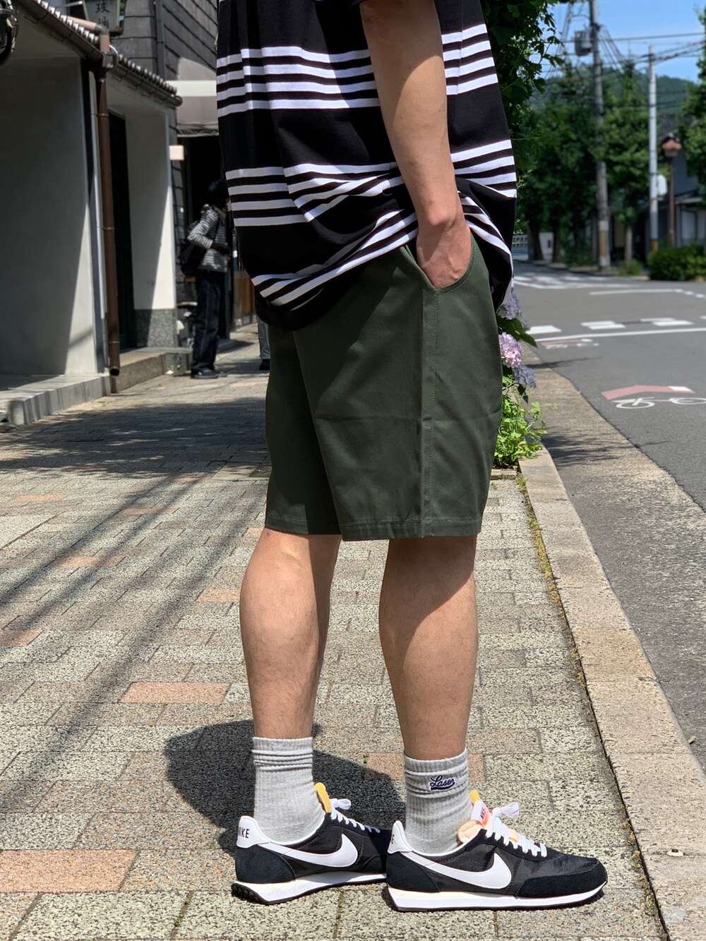 ブラック系のTシャツ/カットソー、グリーン系のチノパンツ、ブラック系のスニーカーを着用したメンズの夏コーディネートの4枚目の写真