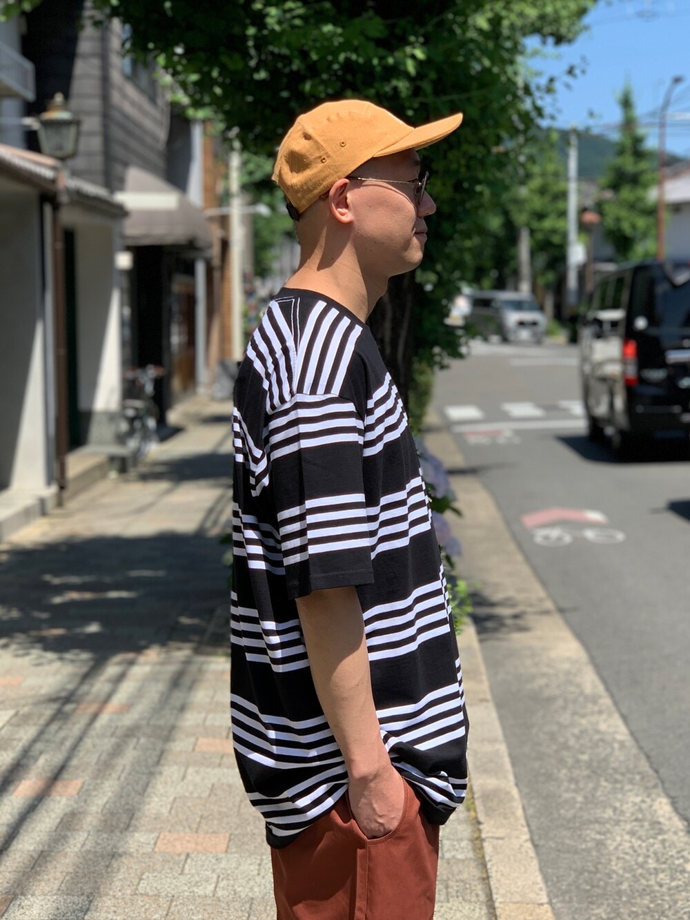 ブラック系のTシャツ/カットソー、ブラウン系のチノパンツ、ブラック系のスニーカーを着用したメンズの夏コーディネートの3枚目の写真