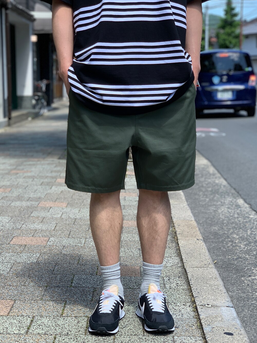 ブラック系のTシャツ/カットソー、グリーン系のチノパンツ、ブラック系のスニーカーを着用したメンズの夏コーディネートの3枚目の写真