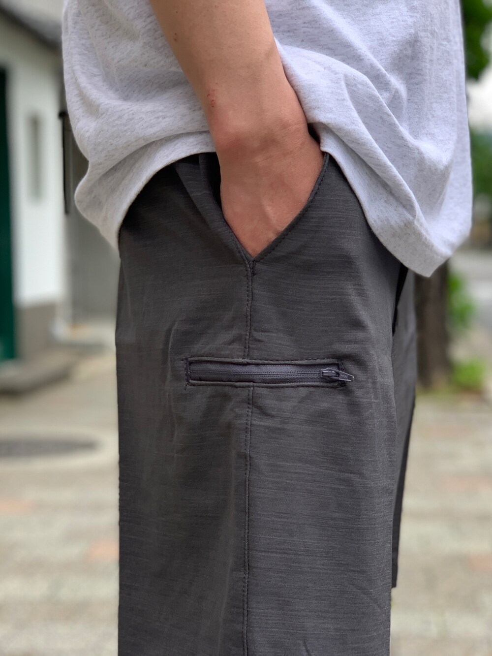 ブラック系のスニーカー、グレー系のチノパンツを着用したメンズの夏コーディネートの4枚目の写真