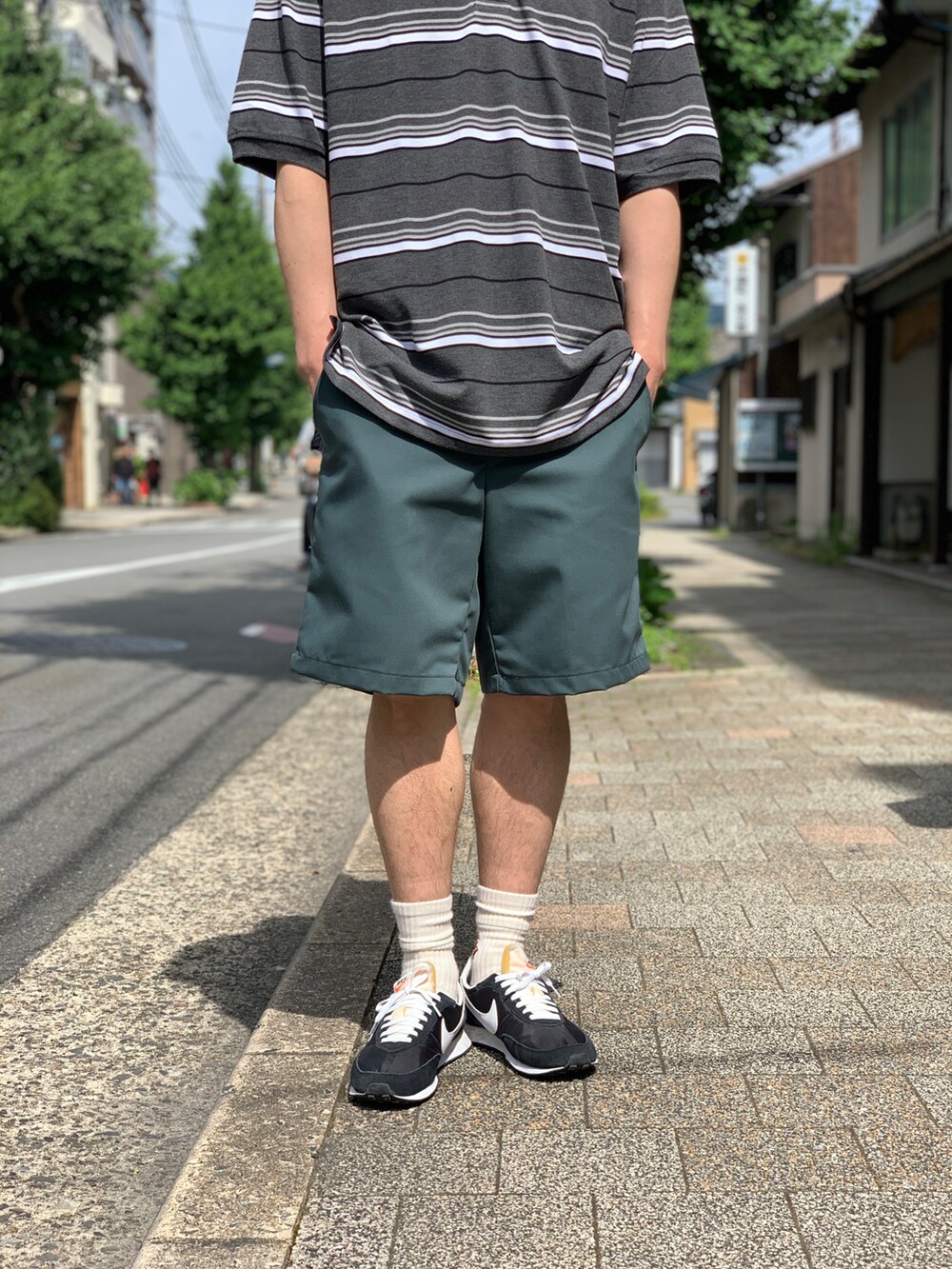 グレー系のポロシャツ、グリーン系のチノパンツ、ブラック系のスニーカーを着用したメンズの秋コーディネートの3枚目の写真