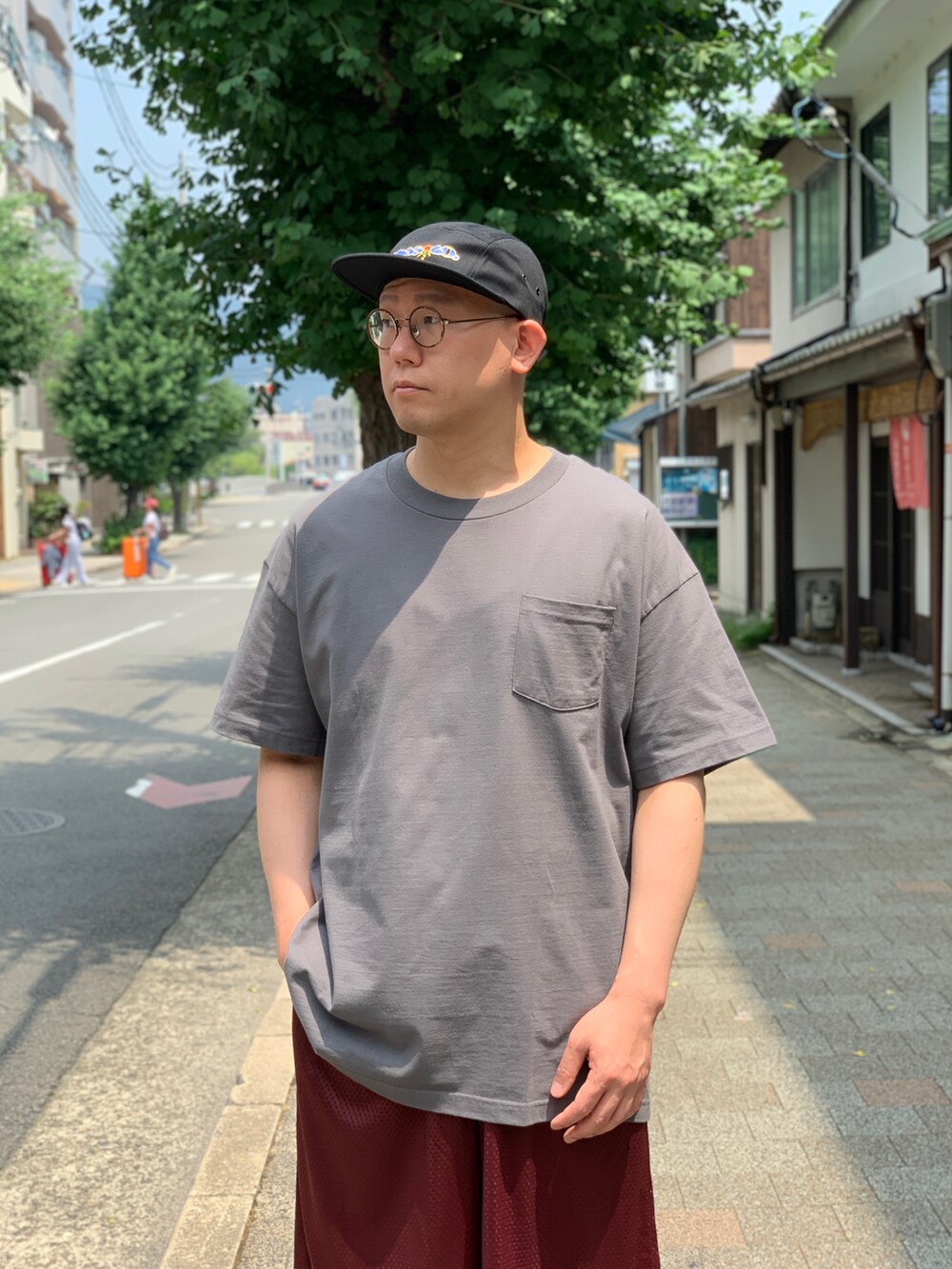 グレー系のTシャツ/カットソー、レッド系のその他パンツ、ブラック系のスニーカーを着用したメンズの夏コーディネートの4枚目の写真