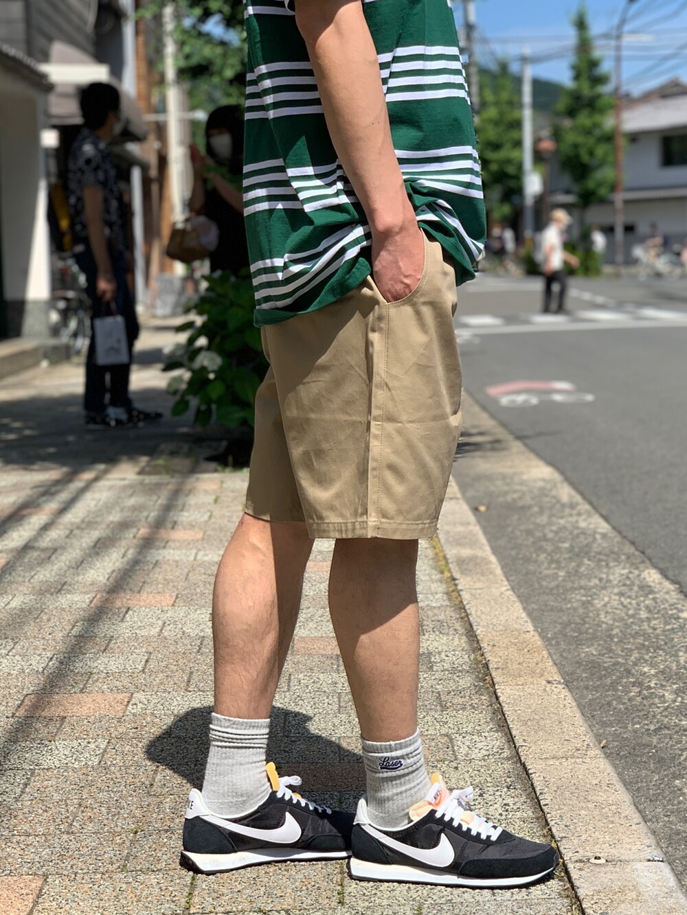 グリーン系のTシャツ/カットソー、ベージュ系のチノパンツ、ブラック系のスニーカーを着用したメンズの夏コーディネートの5枚目の写真