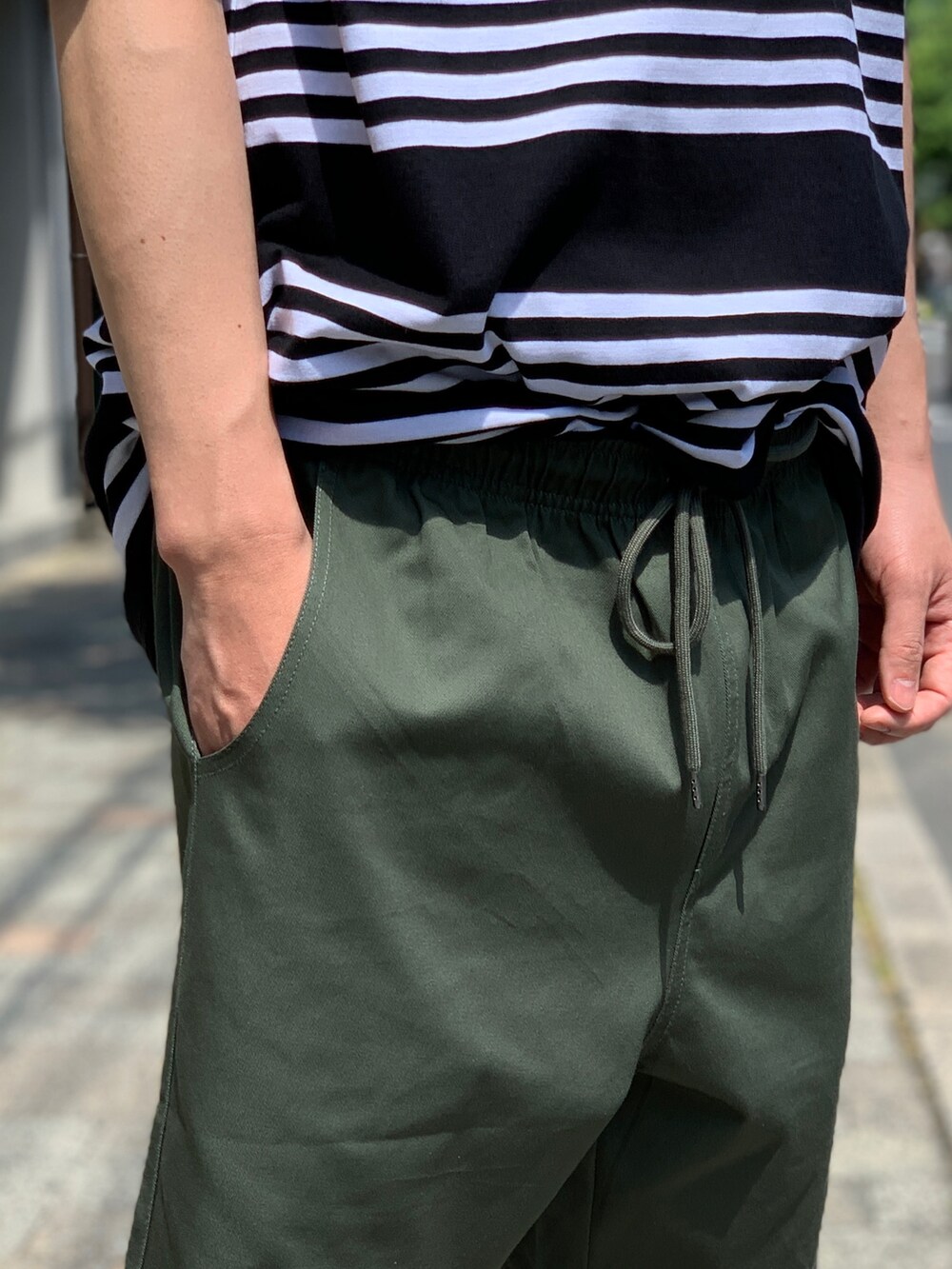 ブラック系のTシャツ/カットソー、グリーン系のチノパンツ、ブラック系のスニーカーを着用したメンズの夏コーディネートの5枚目の写真