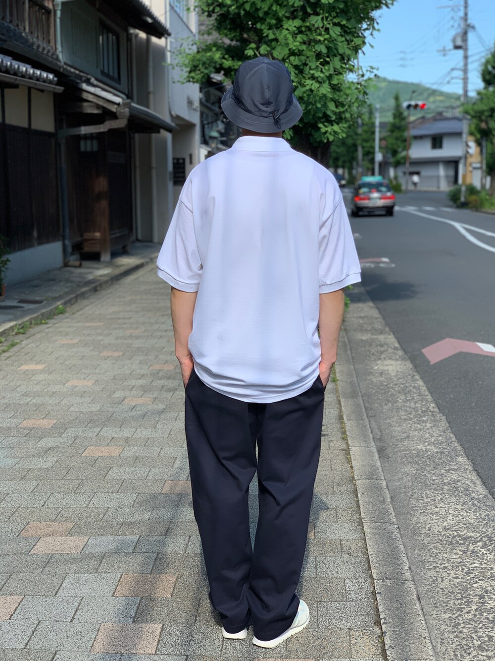 ホワイト系のポロシャツ、ブルー系のチノパンツを着用したメンズの夏コーディネートの2枚目の写真