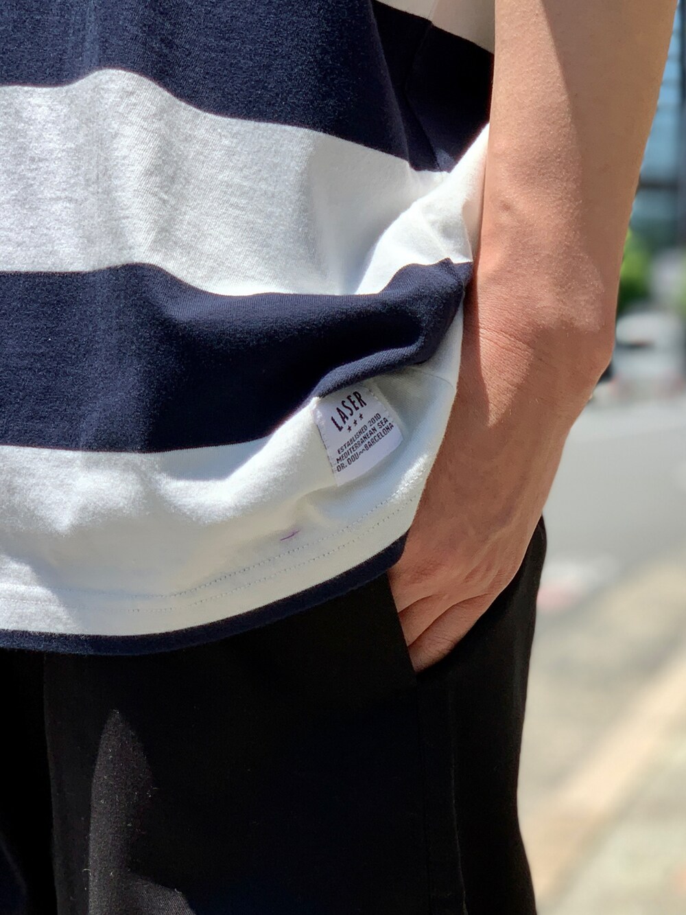 ブラック系のスニーカー、ブルー系のTシャツ/カットソー、ブラック系のチノパンツを着用したメンズの夏コーディネートの5枚目の写真