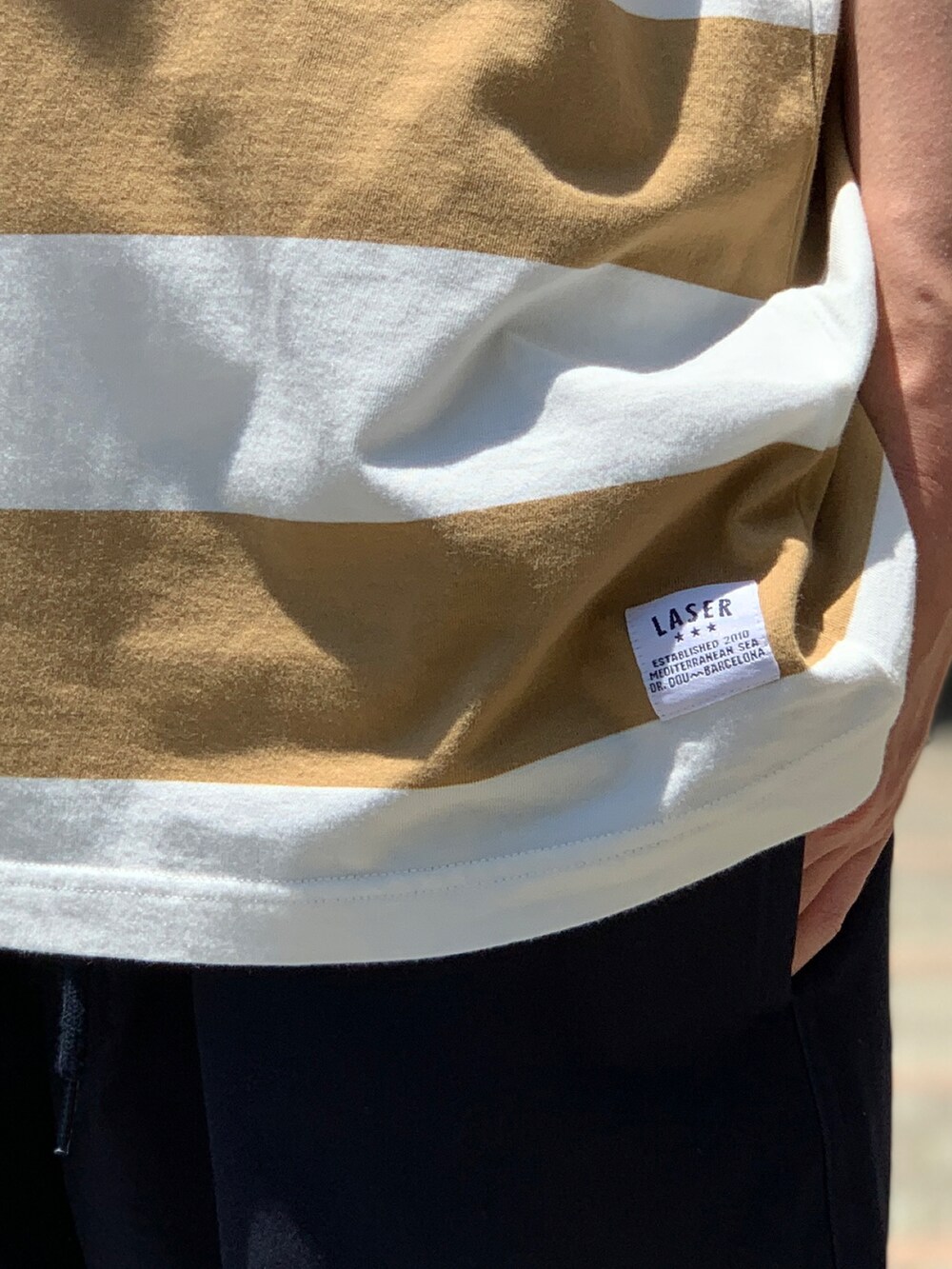 ブラウン系のTシャツ/カットソー、ブルー系のチノパンツ、ベージュ系のスニーカーを着用したメンズの夏コーディネートの4枚目の写真