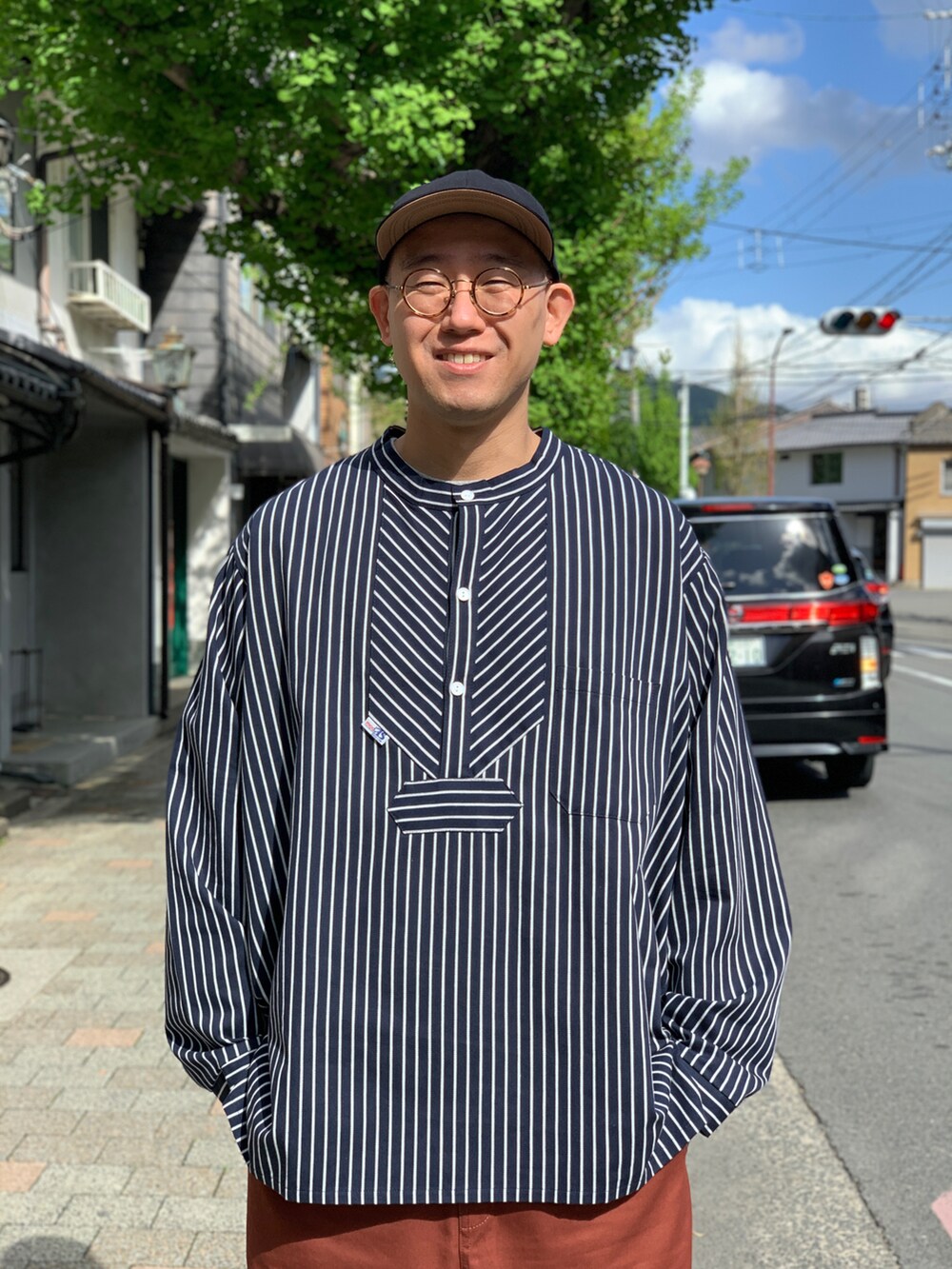 ブラック系のシャツ/ブラウス、ブラウン系のチノパンツ、ブラック系のスニーカーを着用したメンズの夏コーディネートの3枚目の写真