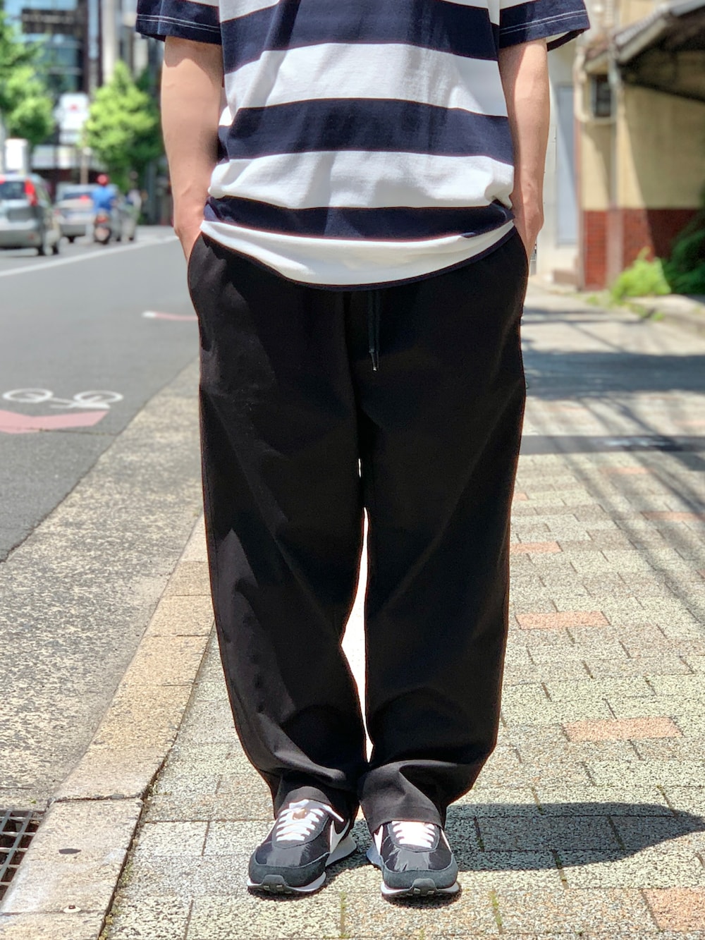 ブラック系のスニーカー、ブルー系のTシャツ/カットソー、ブラック系のチノパンツを着用したメンズの夏コーディネートの4枚目の写真