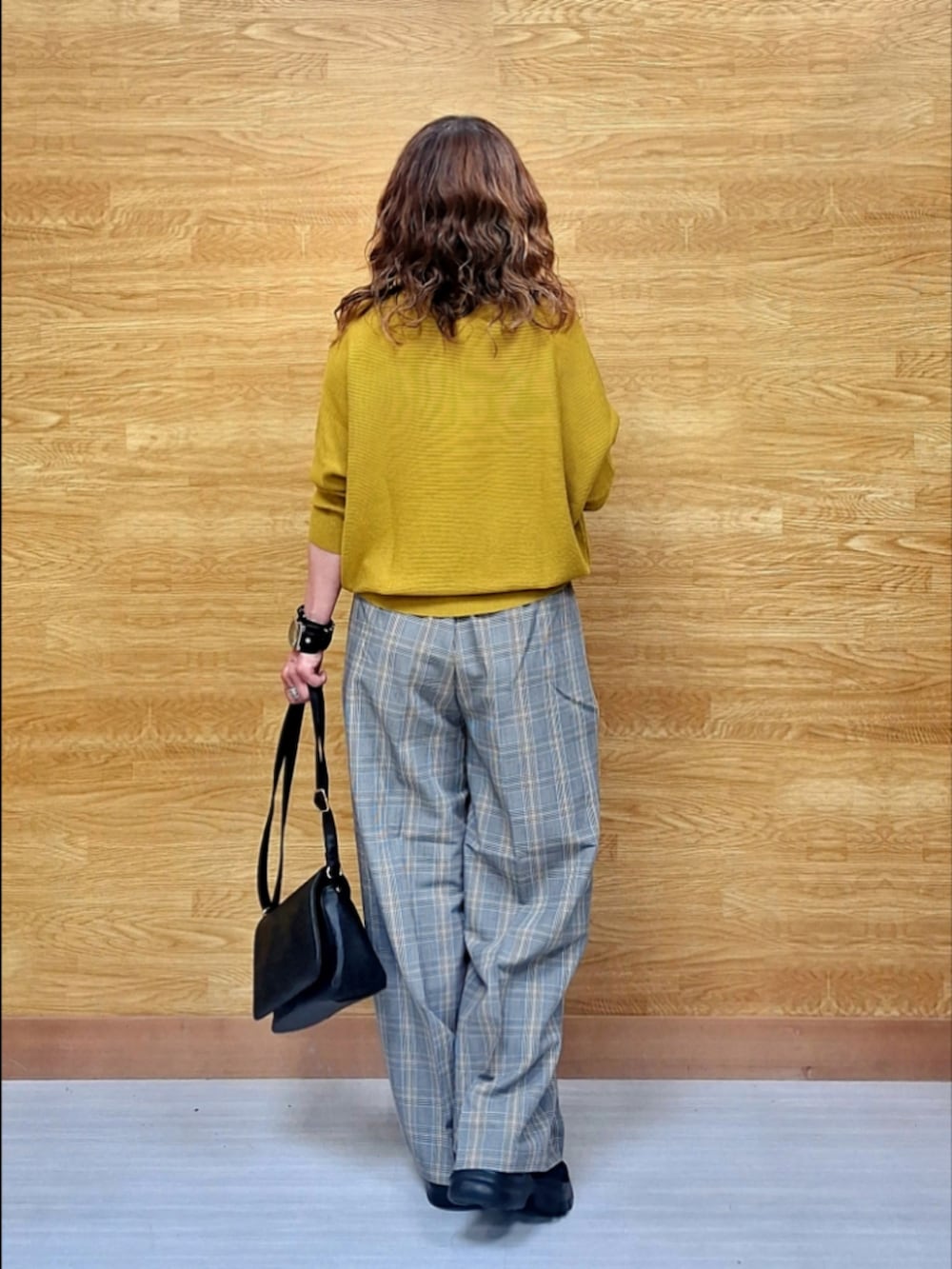 イエロー系のニット/セーター、グレー系のその他パンツ、ブラック系のショルダーバッグを着用したレディースの秋コーディネートの3枚目の写真