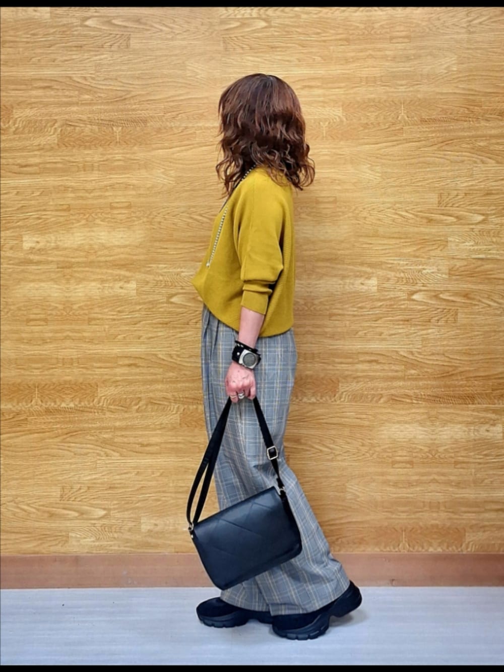 イエロー系のニット/セーター、グレー系のその他パンツ、ブラック系のショルダーバッグを着用したレディースの秋コーディネートの2枚目の写真