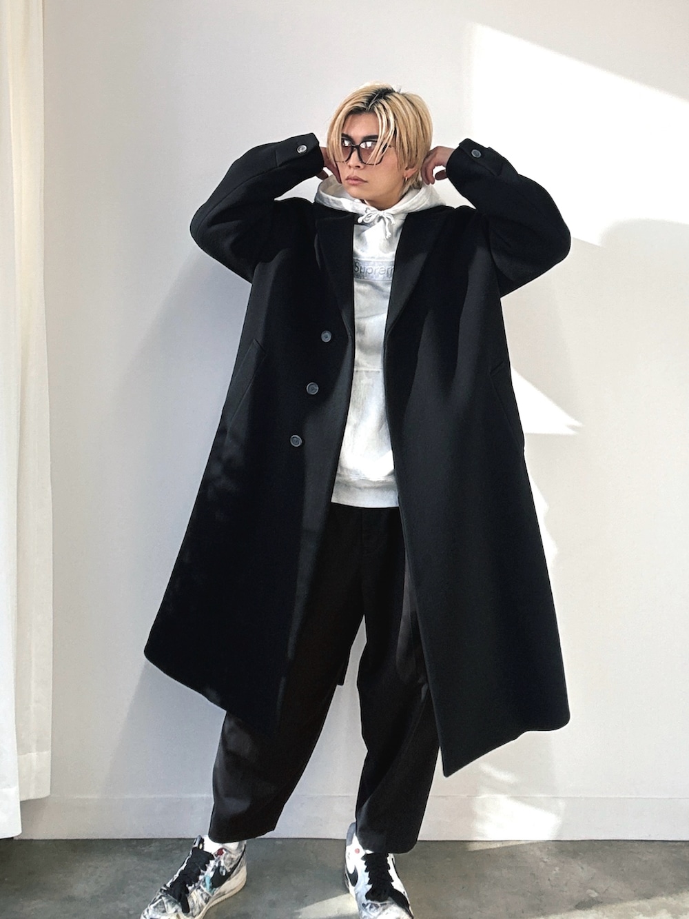 ブラック系のチェスターコート、ホワイト系のスニーカー、ホワイト系のスニーカーを着用したメンズの冬コーディネートの2枚目の写真