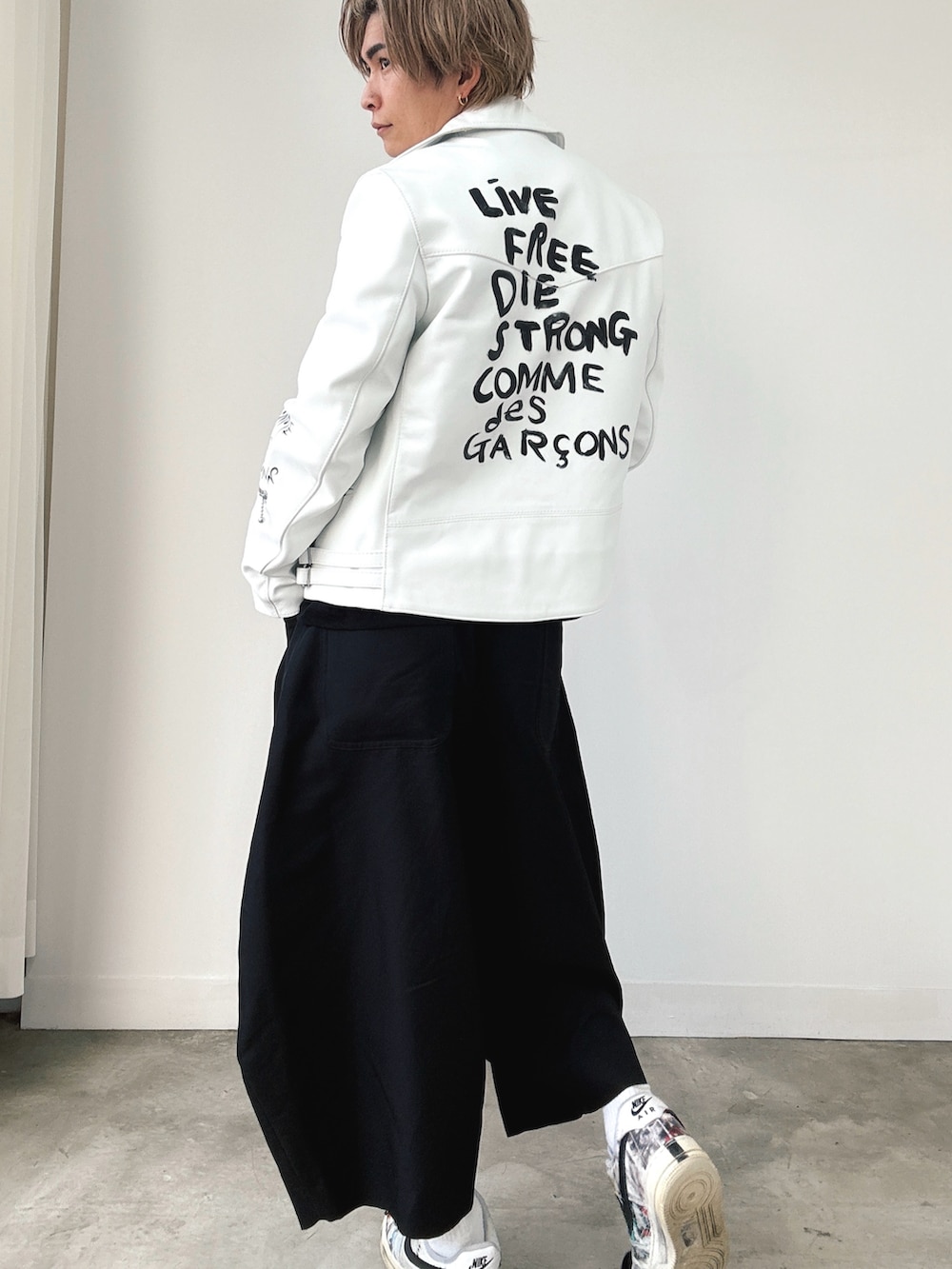 ホワイト系のライダースジャケット、ブラック系のTシャツ/カットソー、ブラック系のスラックスを着用したメンズの秋コーディネートの2枚目の写真