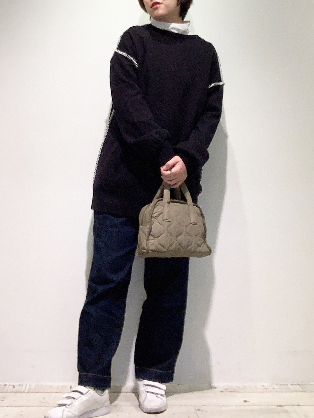 ブルー系のデニムパンツ、ホワイト系のスニーカー、グリーン系のショルダーバッグを着用したレディースの冬コーディネートの2枚目の写真