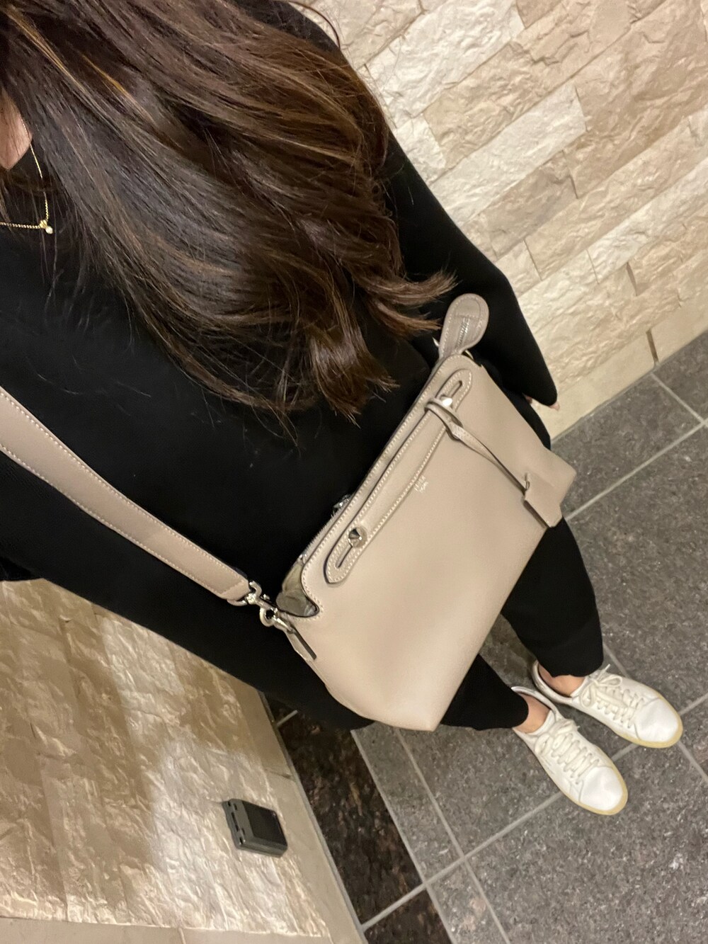 ベージュ系のショルダーバッグ、ホワイト系のスニーカー、ブラック系のトップスを着用したレディースの秋コーディネートの2枚目の写真