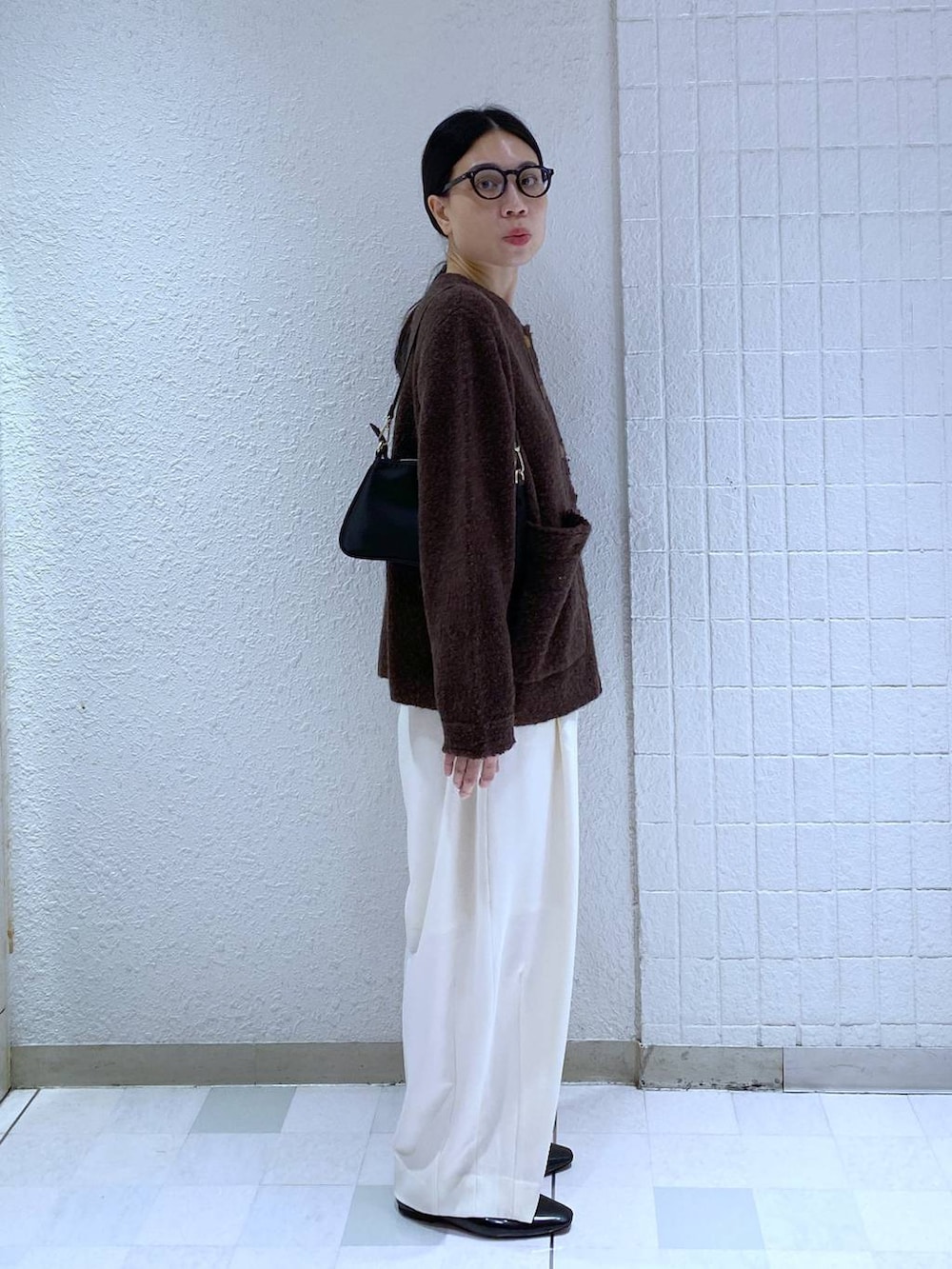 ホワイト系のスラックス、ホワイト系のTシャツ/カットソー、ブラック系のショルダーバッグを着用したレディースの秋コーディネートの4枚目の写真