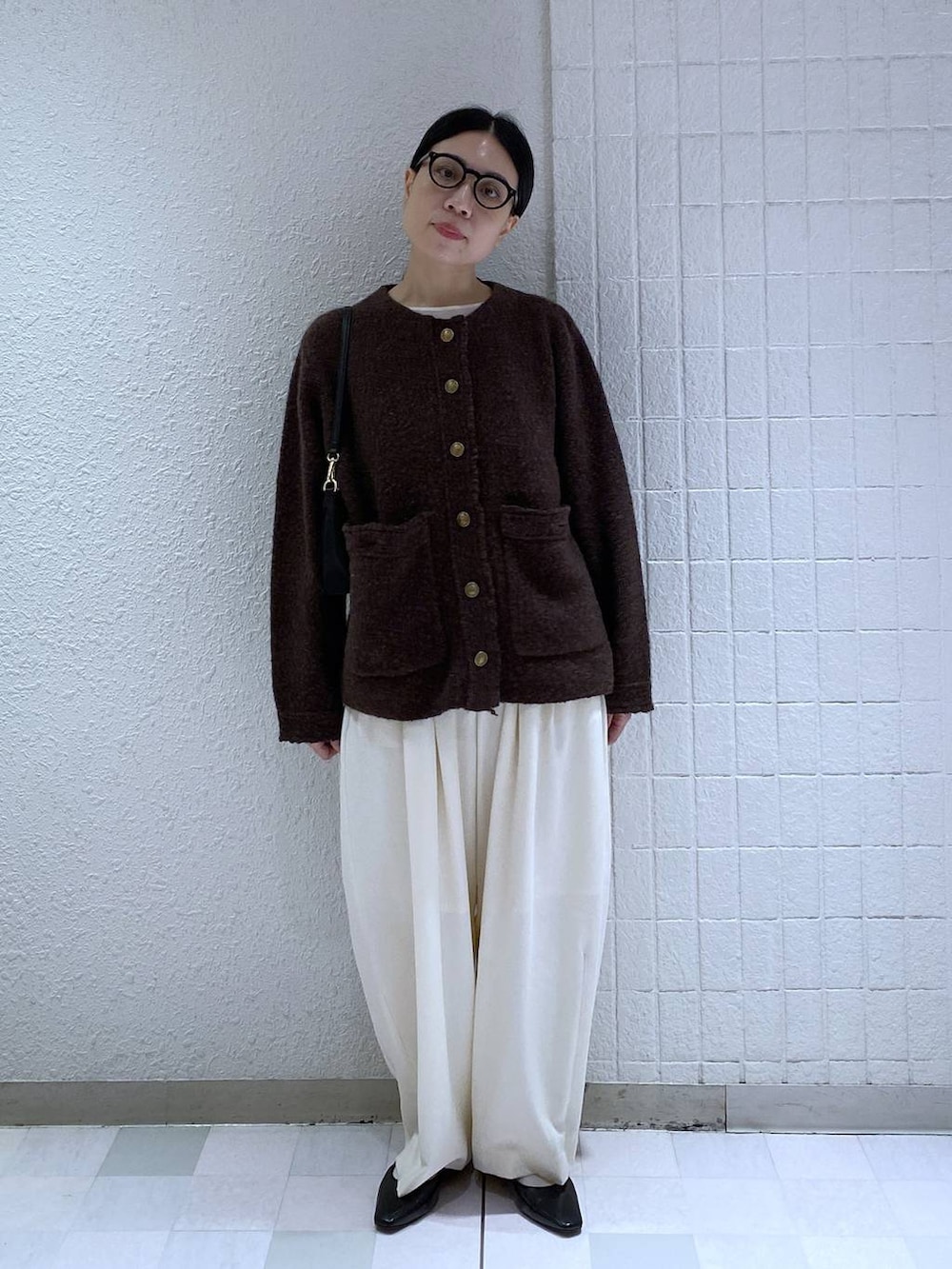 ホワイト系のスラックス、ホワイト系のTシャツ/カットソー、ブラック系のショルダーバッグを着用したレディースの秋コーディネートの3枚目の写真
