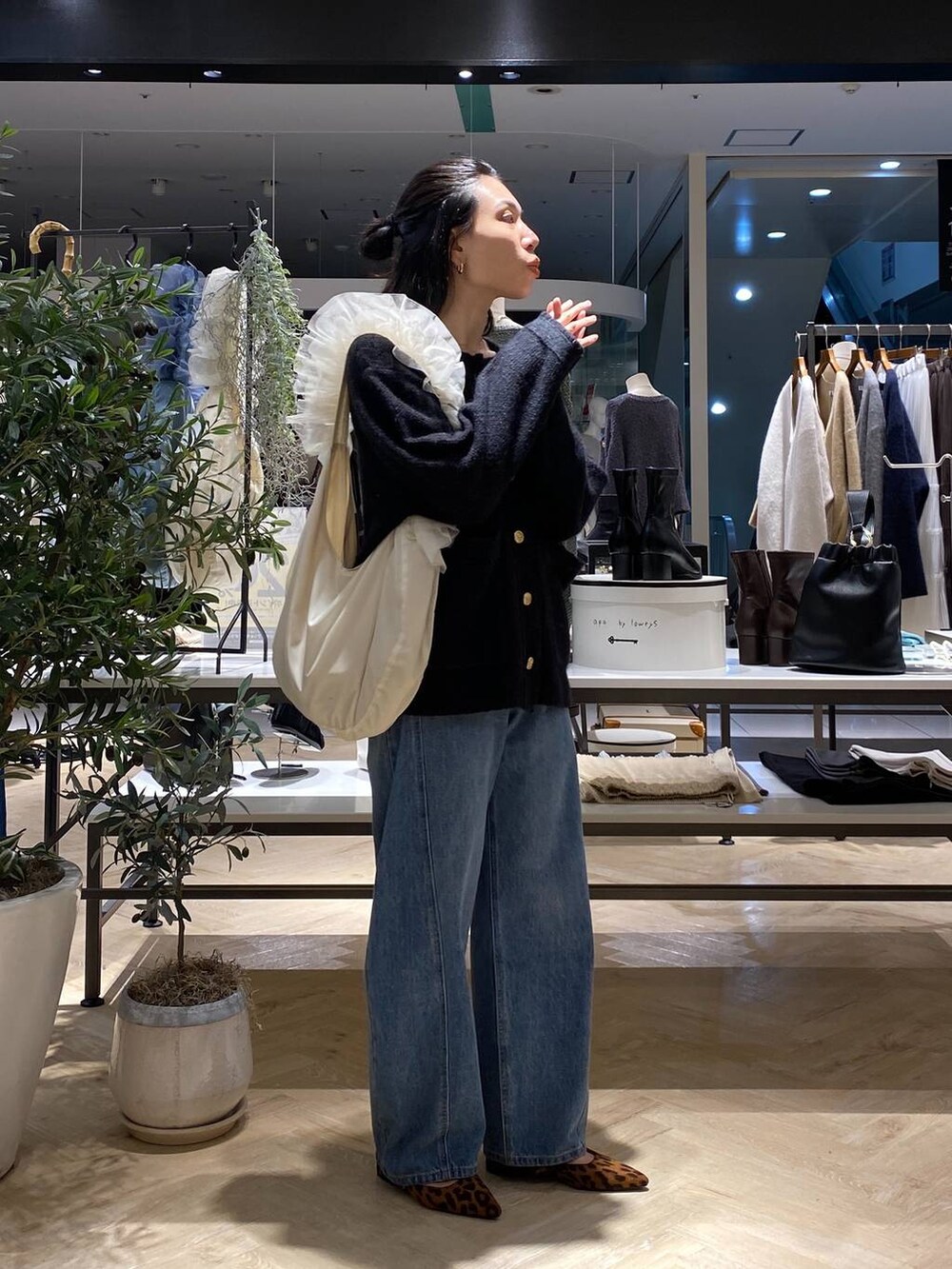 ブラック系のカーディガン/ボレロ、ホワイト系のショルダーバッグ、ブルー系のデニムパンツを着用したレディースの秋コーディネートの3枚目の写真