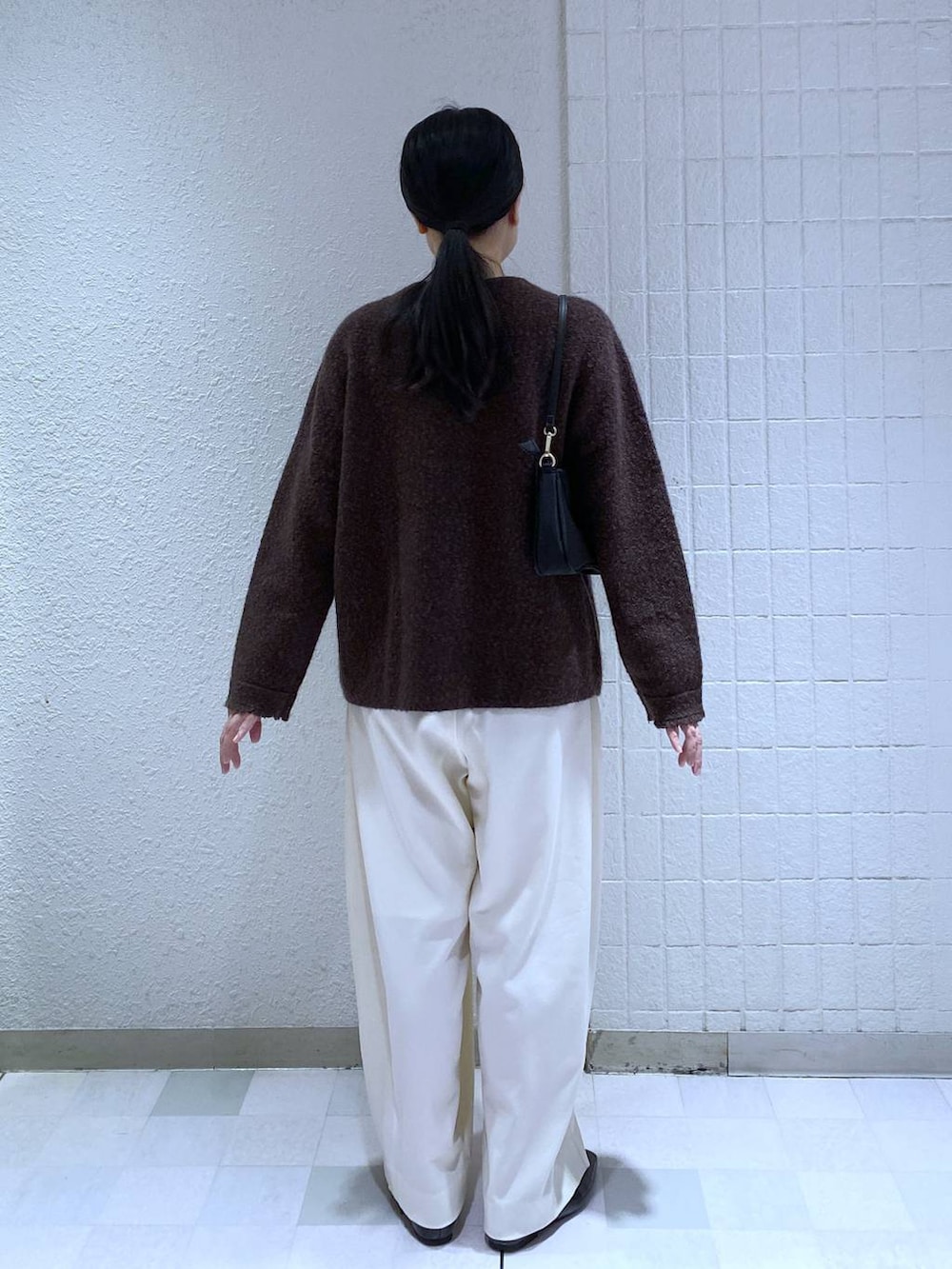 ホワイト系のスラックス、ホワイト系のTシャツ/カットソー、ブラック系のショルダーバッグを着用したレディースの秋コーディネートの5枚目の写真