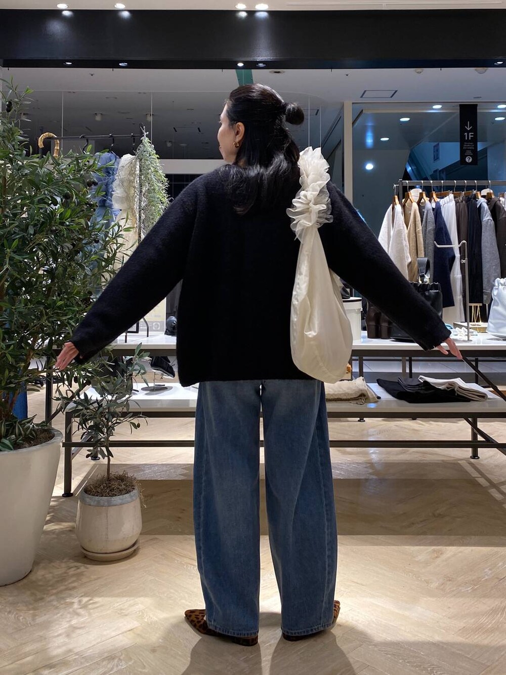 ブラック系のカーディガン/ボレロ、ホワイト系のショルダーバッグ、ブルー系のデニムパンツを着用したレディースの秋コーディネートの5枚目の写真