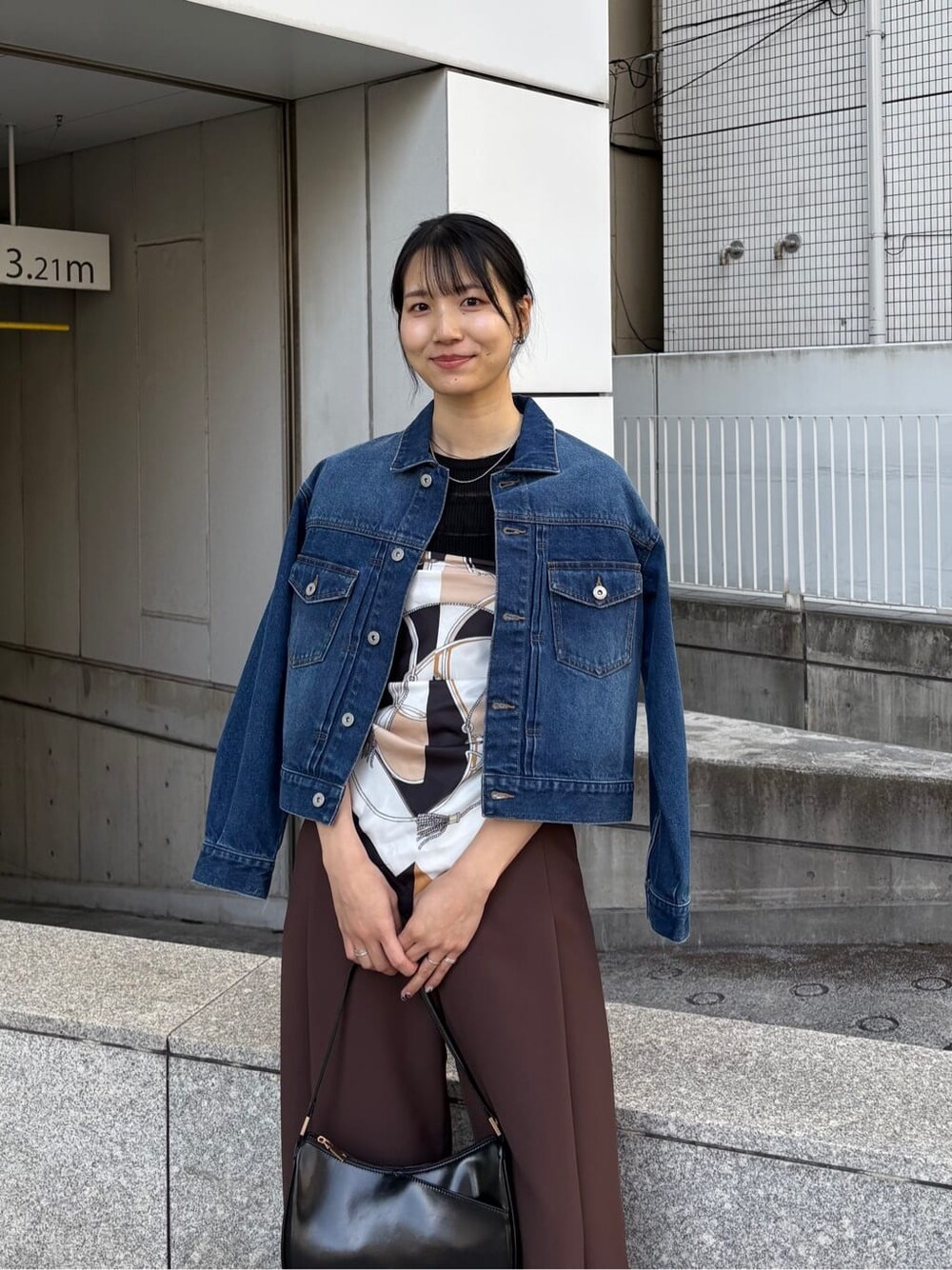 ブルー系のデニムジャケット、ブラック系のニット/セーター、ブラック系のショルダーバッグを着用したレディースの春コーディネートの8枚目の写真