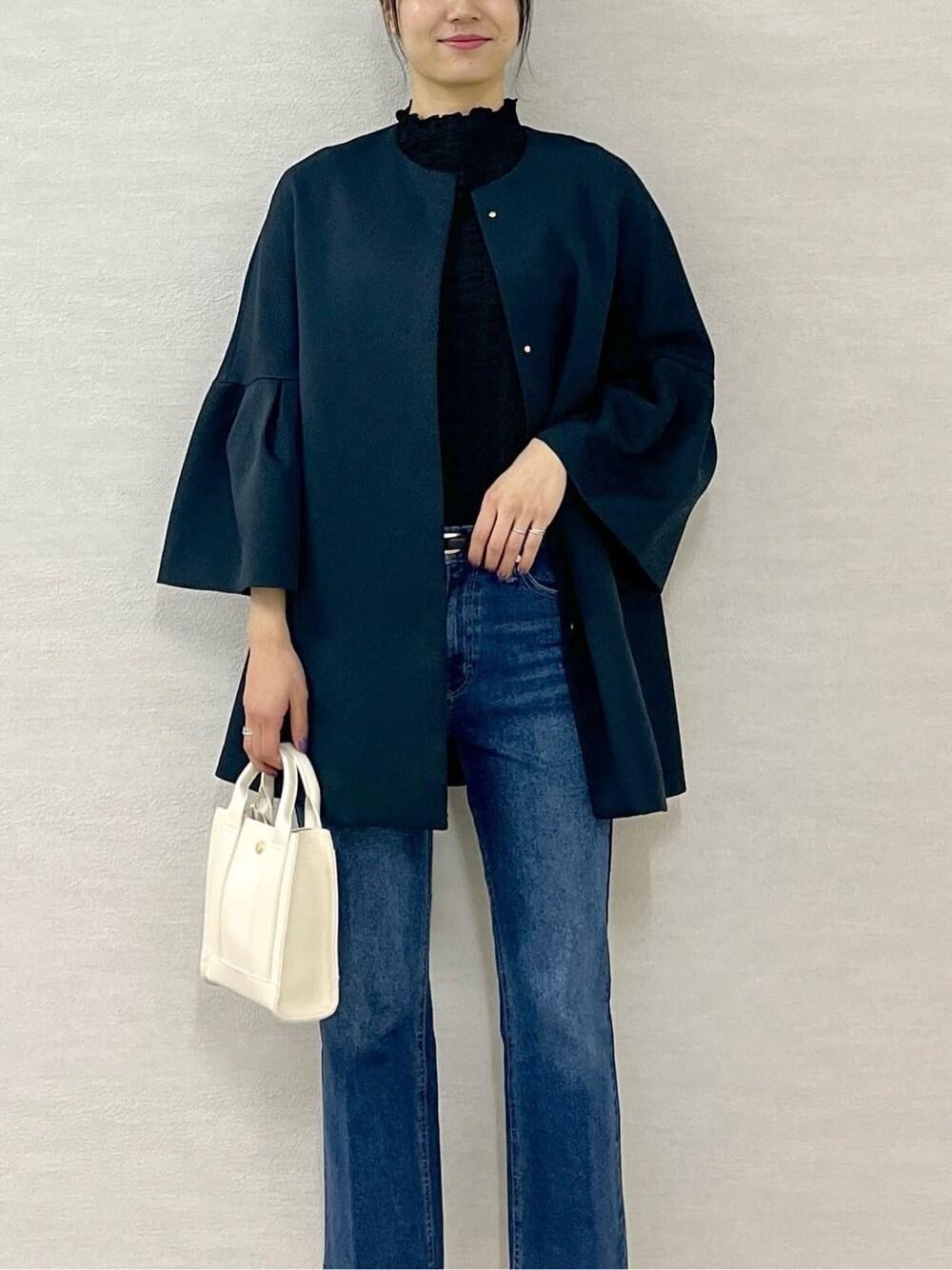 ブルー系のノーカラーコート、ブラック系のTシャツ/カットソー、ブルー系のデニムパンツを着用したレディースの冬コーディネートの7枚目の写真