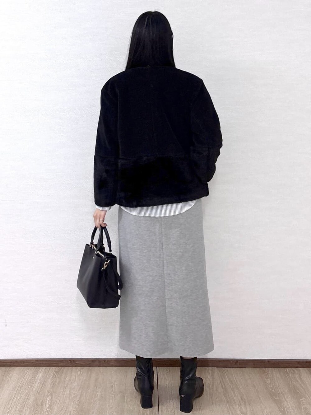 ブラック系のノーカラーコート、レッド系のニット/セーター、ホワイト系のTシャツ/カットソーを着用したレディースの冬コーディネートの5枚目の写真