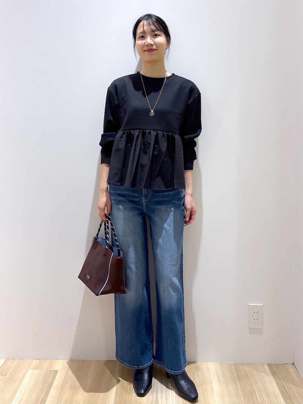 ブラック系のTシャツ/カットソー、ブルー系のデニムパンツ、ブラウン系のトートバッグを着用したレディースの秋コーディネートの9枚目の写真