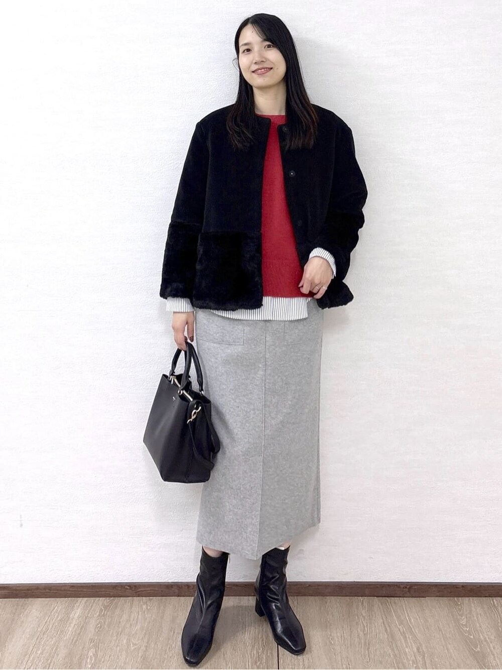 ブラック系のノーカラーコート、レッド系のニット/セーター、ホワイト系のTシャツ/カットソーを着用したレディースの冬コーディネートの3枚目の写真