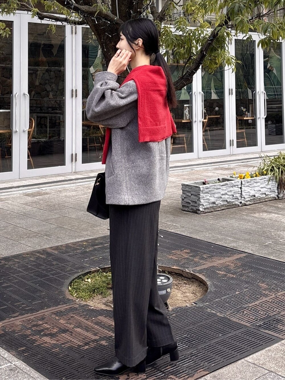 グレー系のノーカラーコート、ブラック系のニット/セーター、グレー系のその他パンツを着用したレディースの冬コーディネートの5枚目の写真