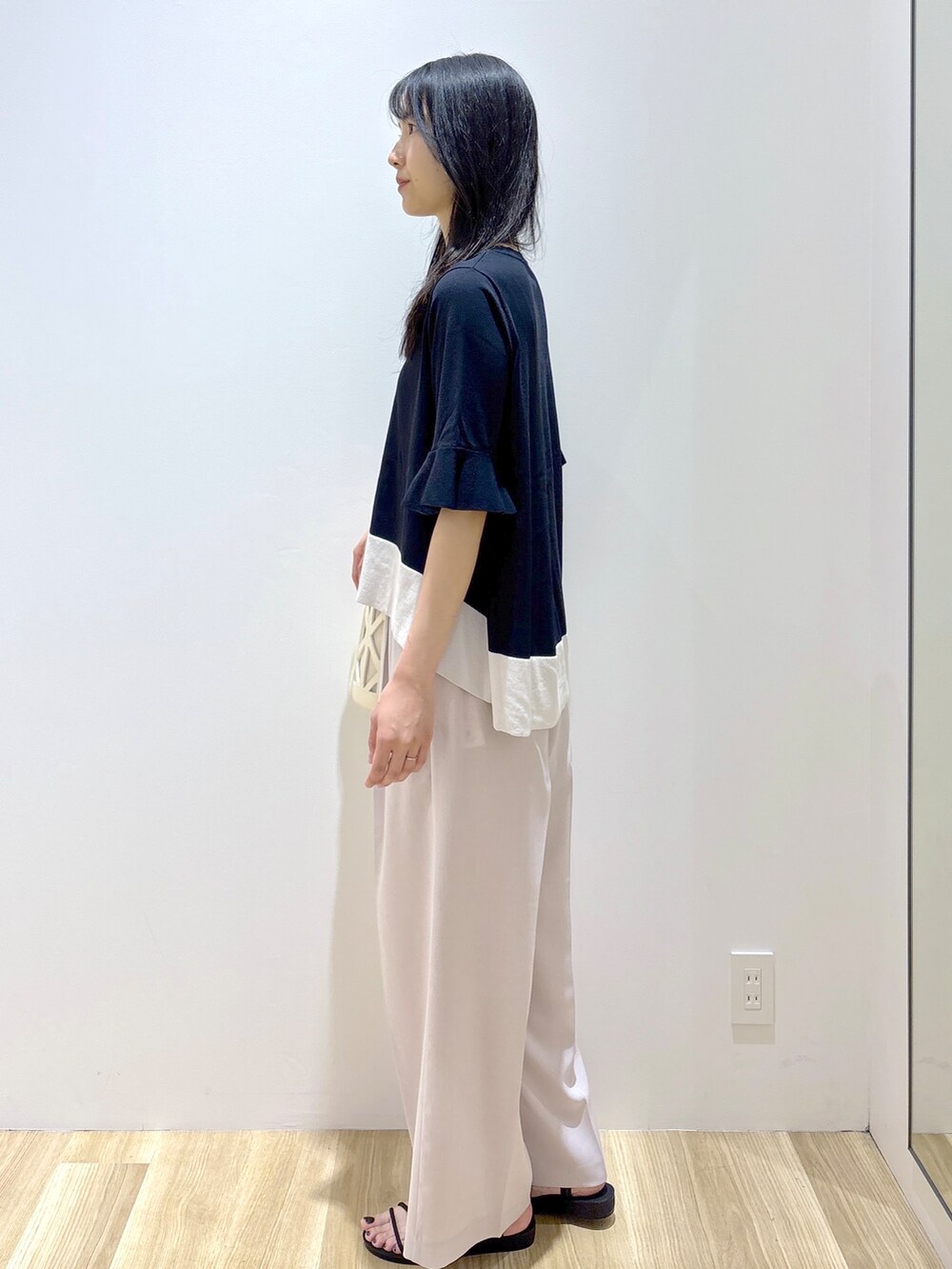 ブラック系のニット/セーター、ベージュ系のその他パンツ、ホワイト系のハンドバッグを着用したレディースの夏コーディネートの3枚目の写真