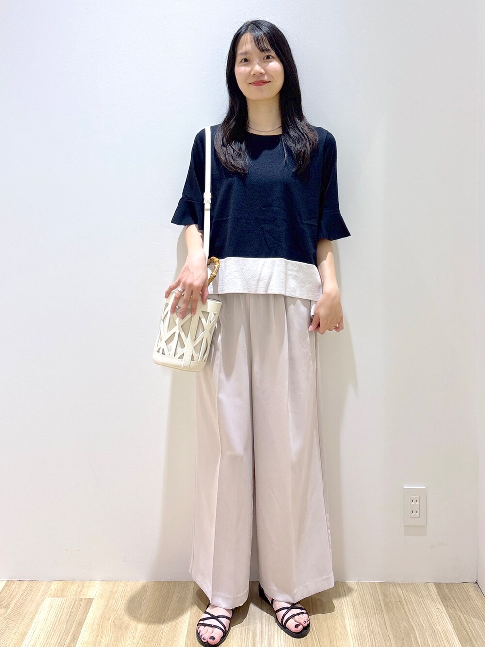 ブラック系のニット/セーター、ベージュ系のその他パンツ、ホワイト系のハンドバッグを着用したレディースの夏コーディネートの9枚目の写真