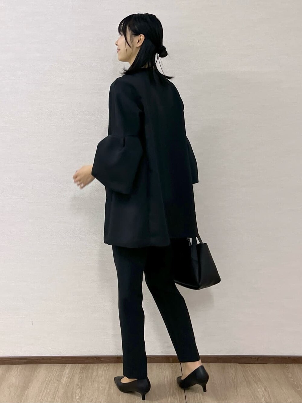 ブラック系のノーカラーコート、ホワイト系のシャツ/ブラウス、ブラック系のその他パンツを着用したレディースの冬コーディネートの6枚目の写真