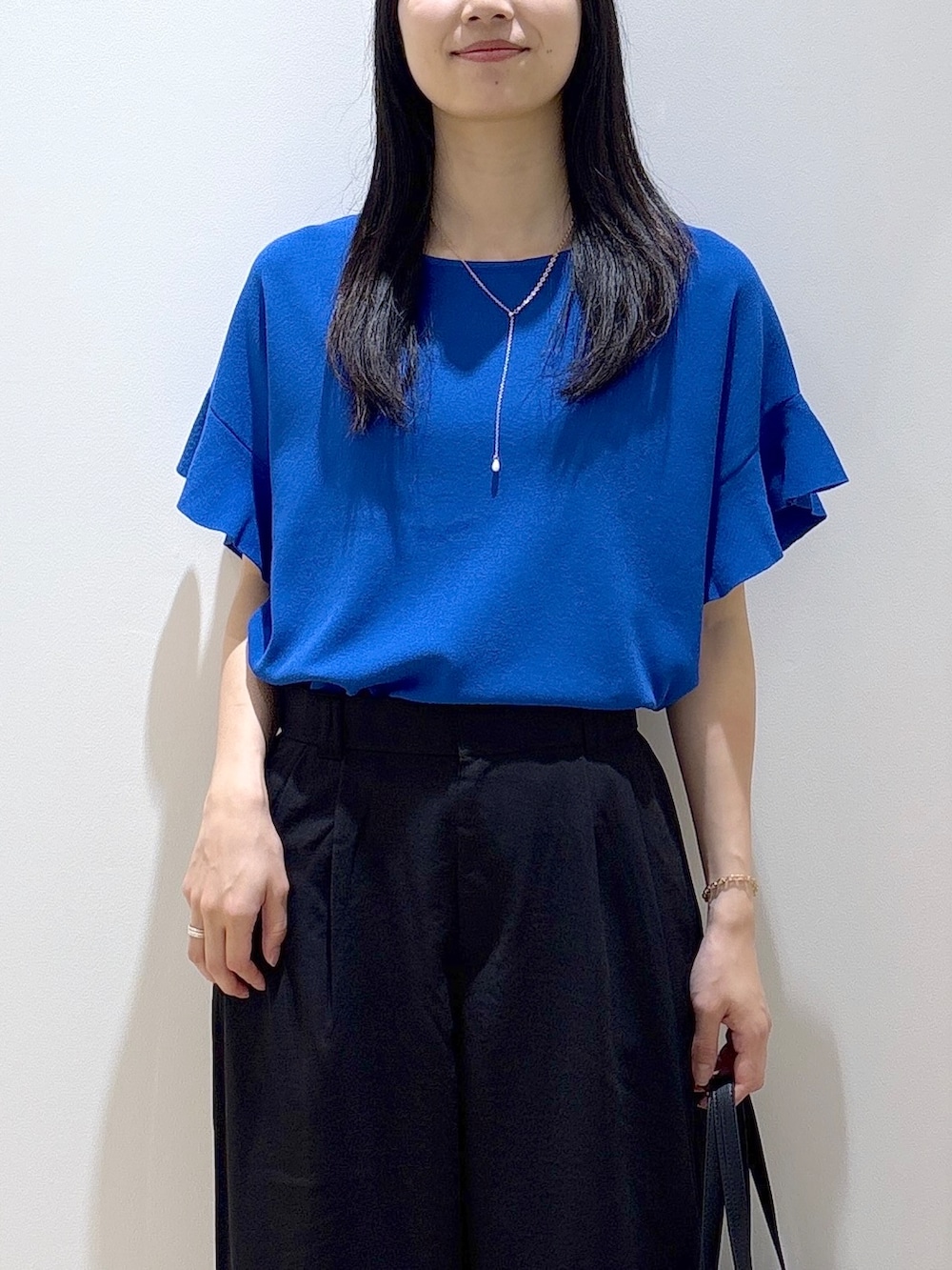 ブルー系のニット/セーター、ブラック系のその他パンツ、ブラック系のトートバッグを着用したレディースの夏コーディネートの6枚目の写真