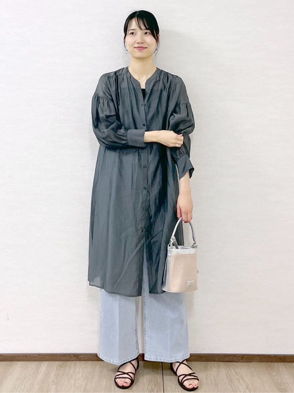 グレー系のワンピース、ブラック系のタンクトップ、ブルー系のデニムパンツを着用したレディースの春コーディネートの7枚目の写真