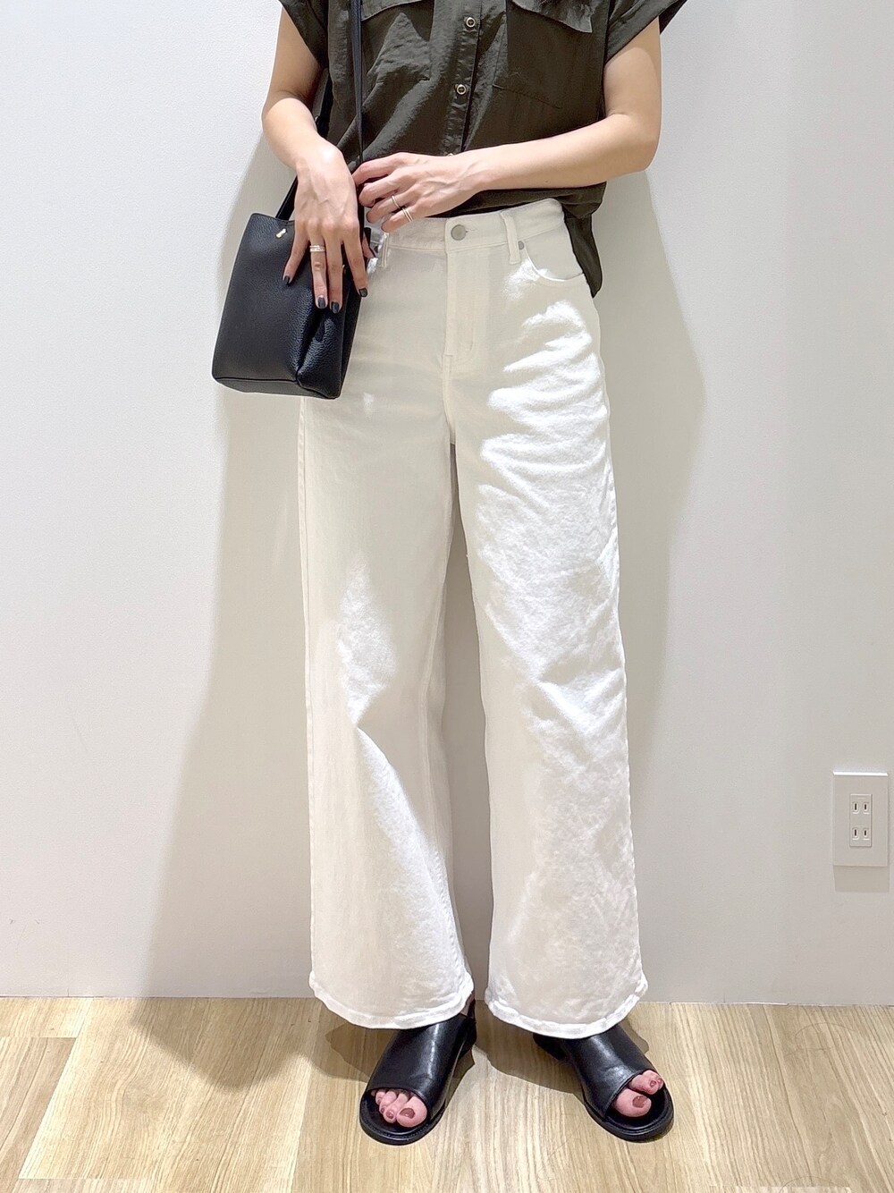 グリーン系のシャツ/ブラウス、ホワイト系のデニムパンツ、ブラック系のショルダーバッグを着用したレディースの夏コーディネートの6枚目の写真